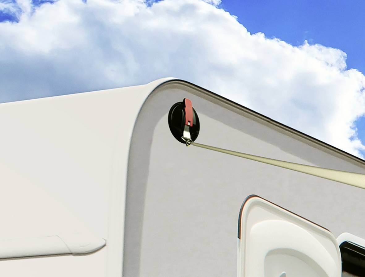 Widok z boku kampera z otwartym oknem dachowym na tle niebieskiego nieba z chmurami.