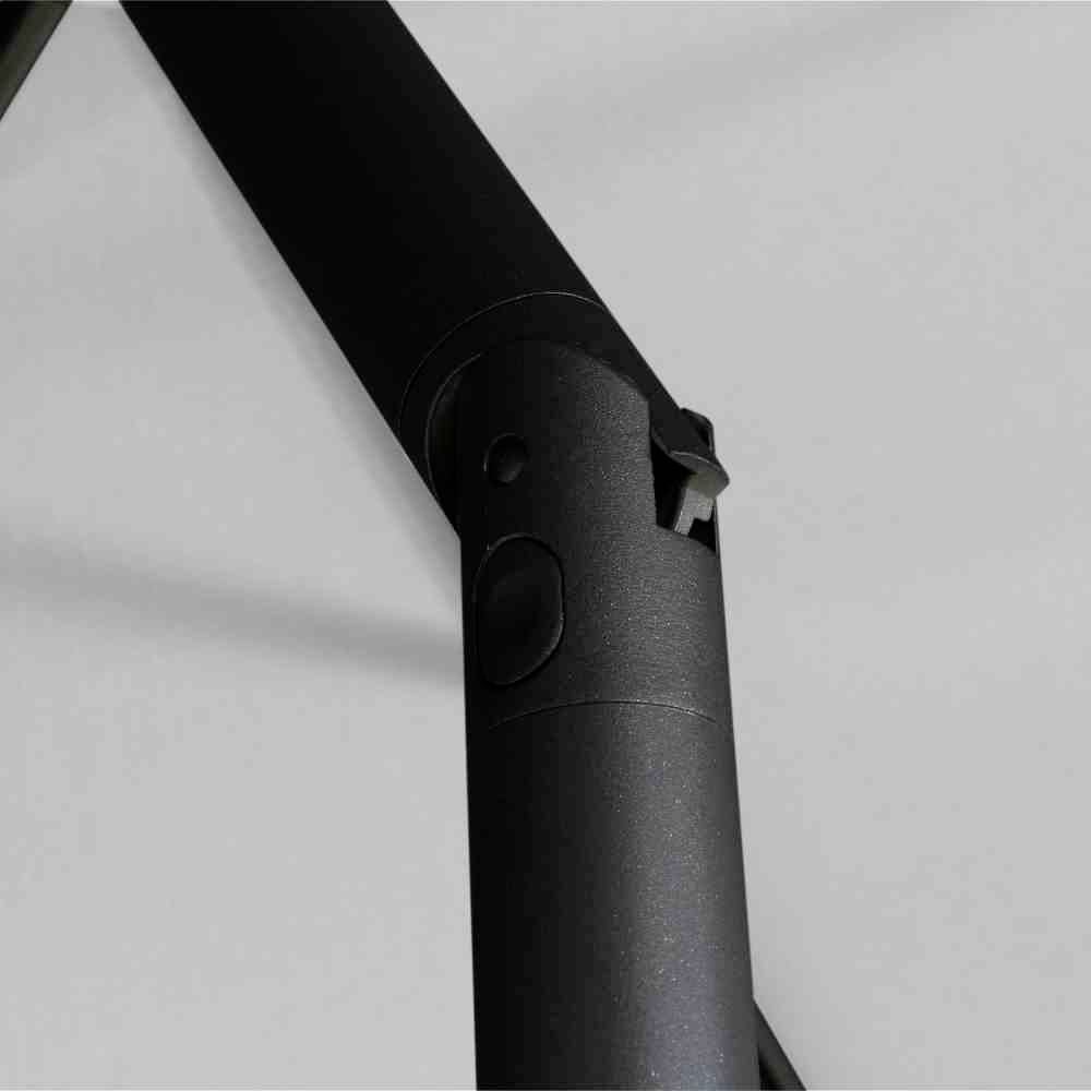 Zbliżenie czarnej metalowej rury z zamocowanym mechanizmem. Tło jest jednobarwne, szare.