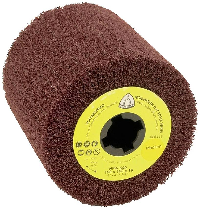 Krążek ścierny z włókniny o brązowo-czerwonej powierzchni z żółtą etykietą, na której widnieje napis 'NON-WOVEN FLAP DISC WHEEL' oraz 'NFW 600 Medium'.
