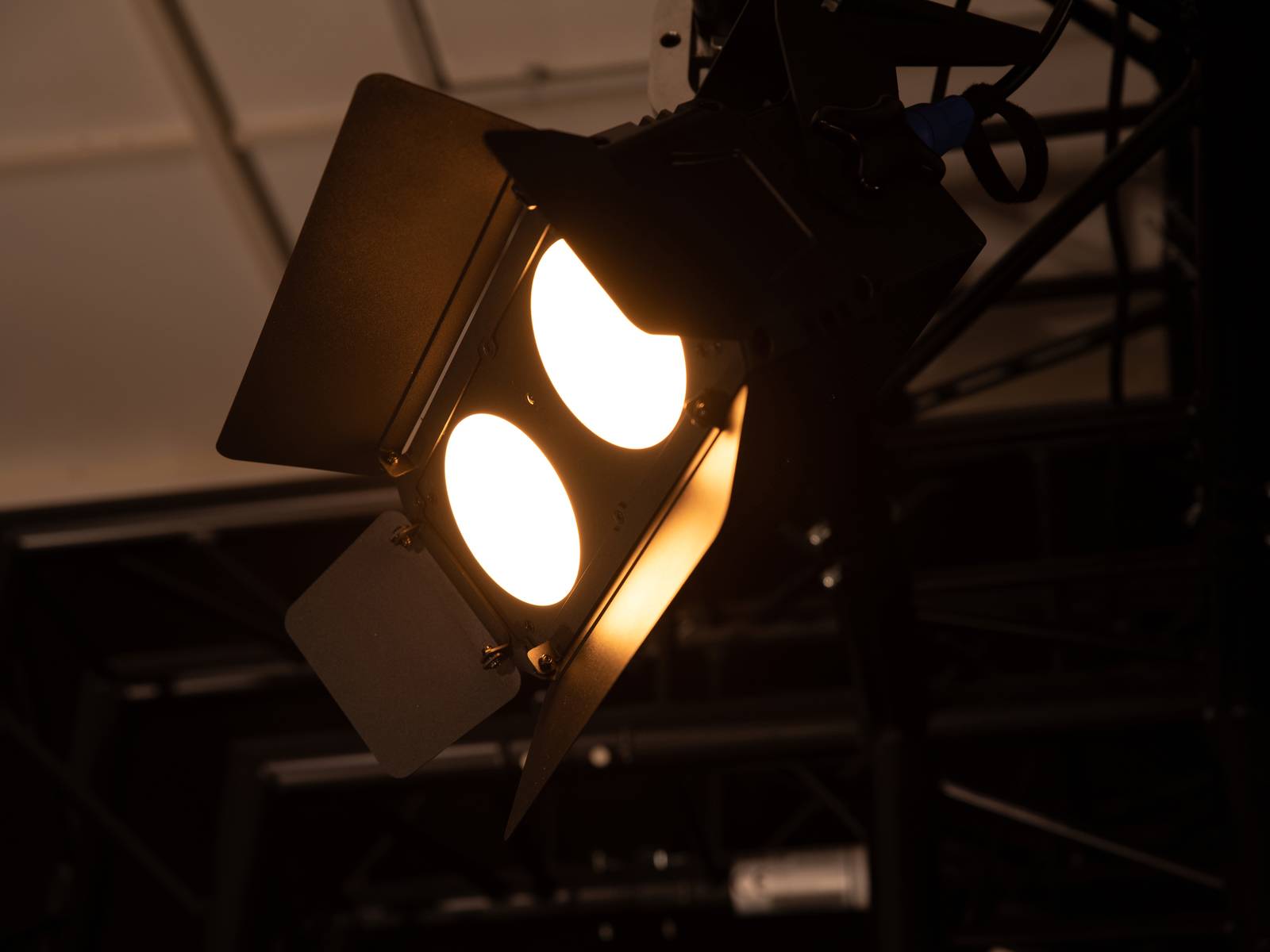 Włączony reflektor sceniczny emitujący dwa jasne strumienie światła. Otoczenie wydaje się ciemne i przemysłowe.