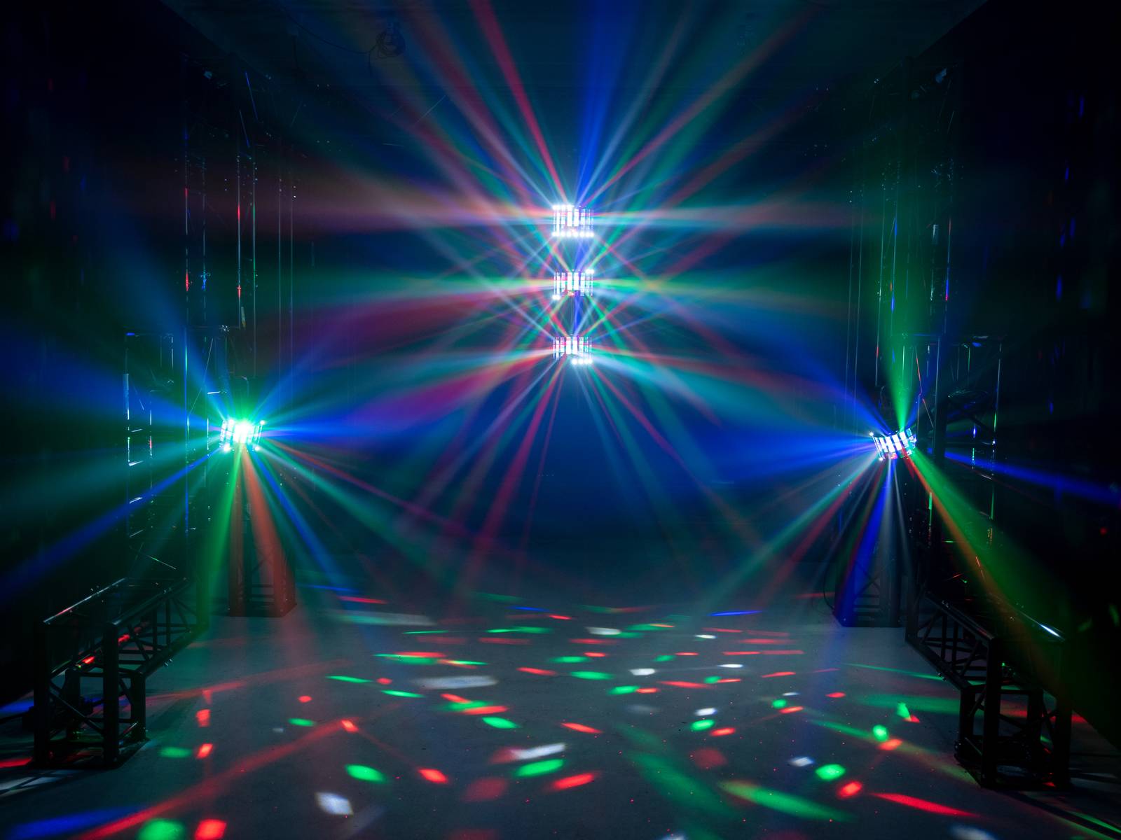 Kolorowe smugi świetlne w ciemnym pomieszczeniu, tworzące żywą i dynamiczną atmosferę, przypominającą klimat dyskoteki.