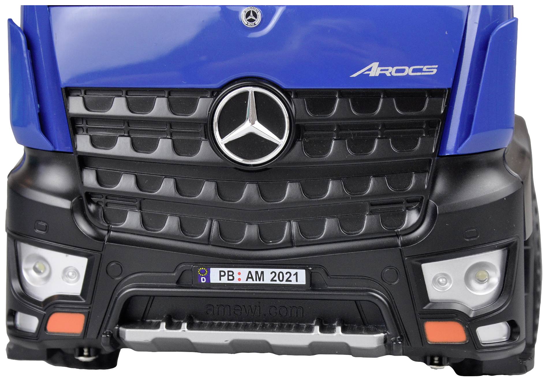 Niebieski model ciężarówki z logo 'Arocs' na przedniej części i emblemem Mercedes-Benz, a poniżej tablicą rejestracyjną 'PB: AM 2021'.