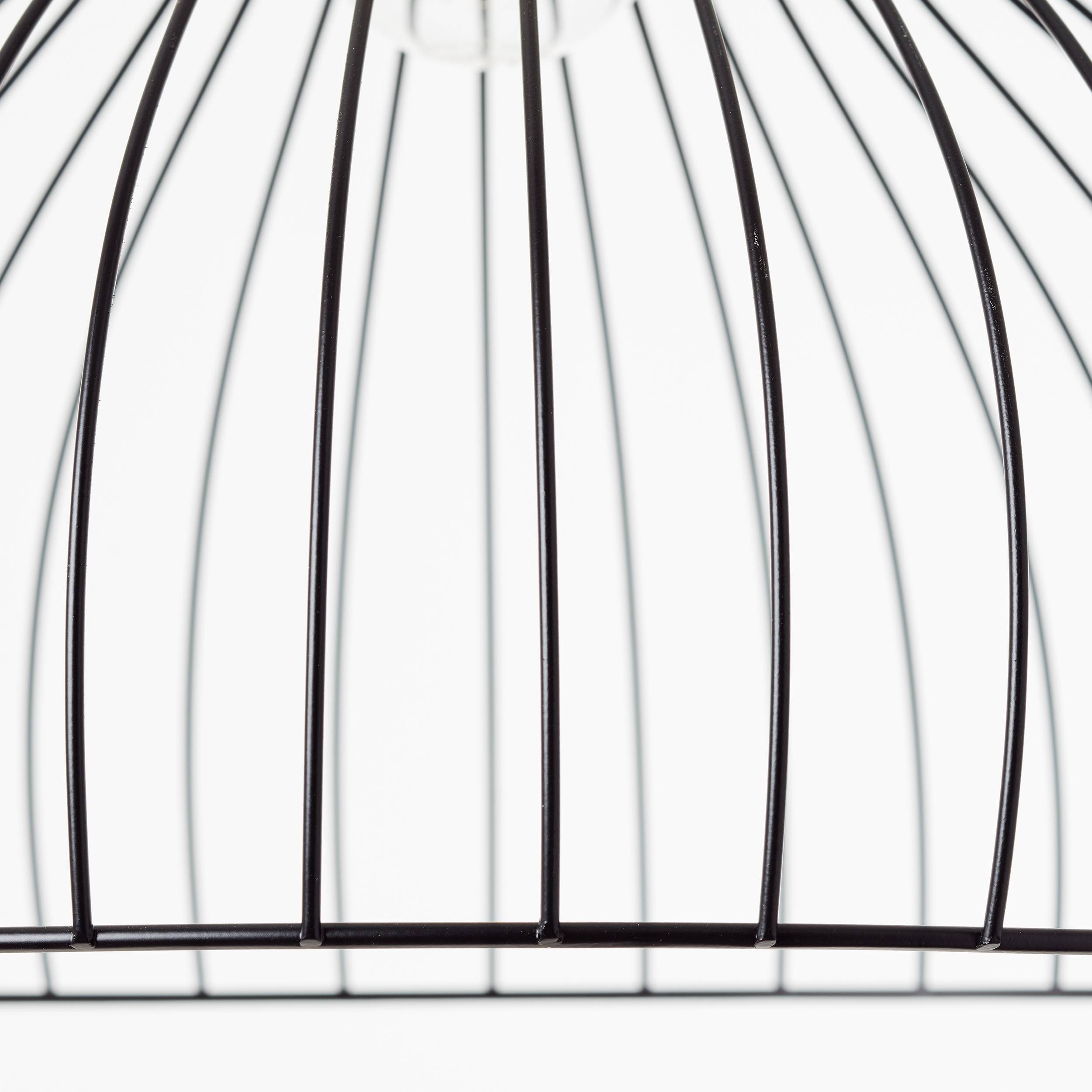 Czarne metalowe pręty pustej klatki dla ptaków sfotografowane z góry na białym tle.
