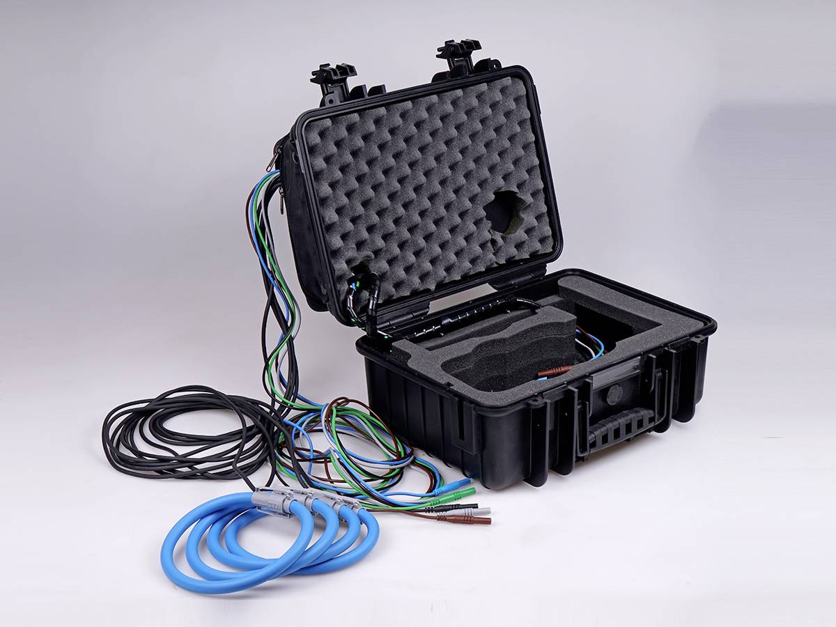 Otwarty czarny kufer z wyściółką z pianki, wewnątrz kable i przewody. Kable biegną na zewnątrz, niebieskie i wielokolorowe.