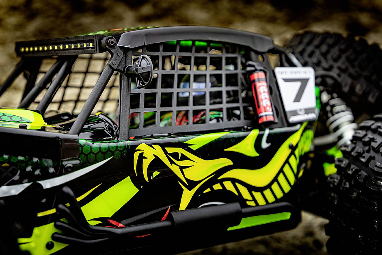 Zbliżenie zdalnie sterowanego samochodu terenowego. Pojazd jest sportowo stylizowany w jaskrawożółtym i zielonym kolorze, wyposażony w duże opony.