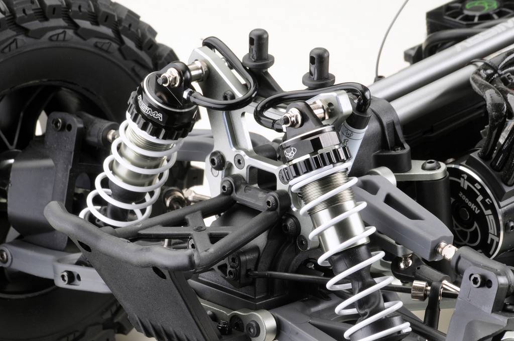 Zbliżenie podwozia modelu samochodu z zawieszeniem i amortyzatorami. Widoczne są wahacze, sprężyny i szczegóły techniczne.