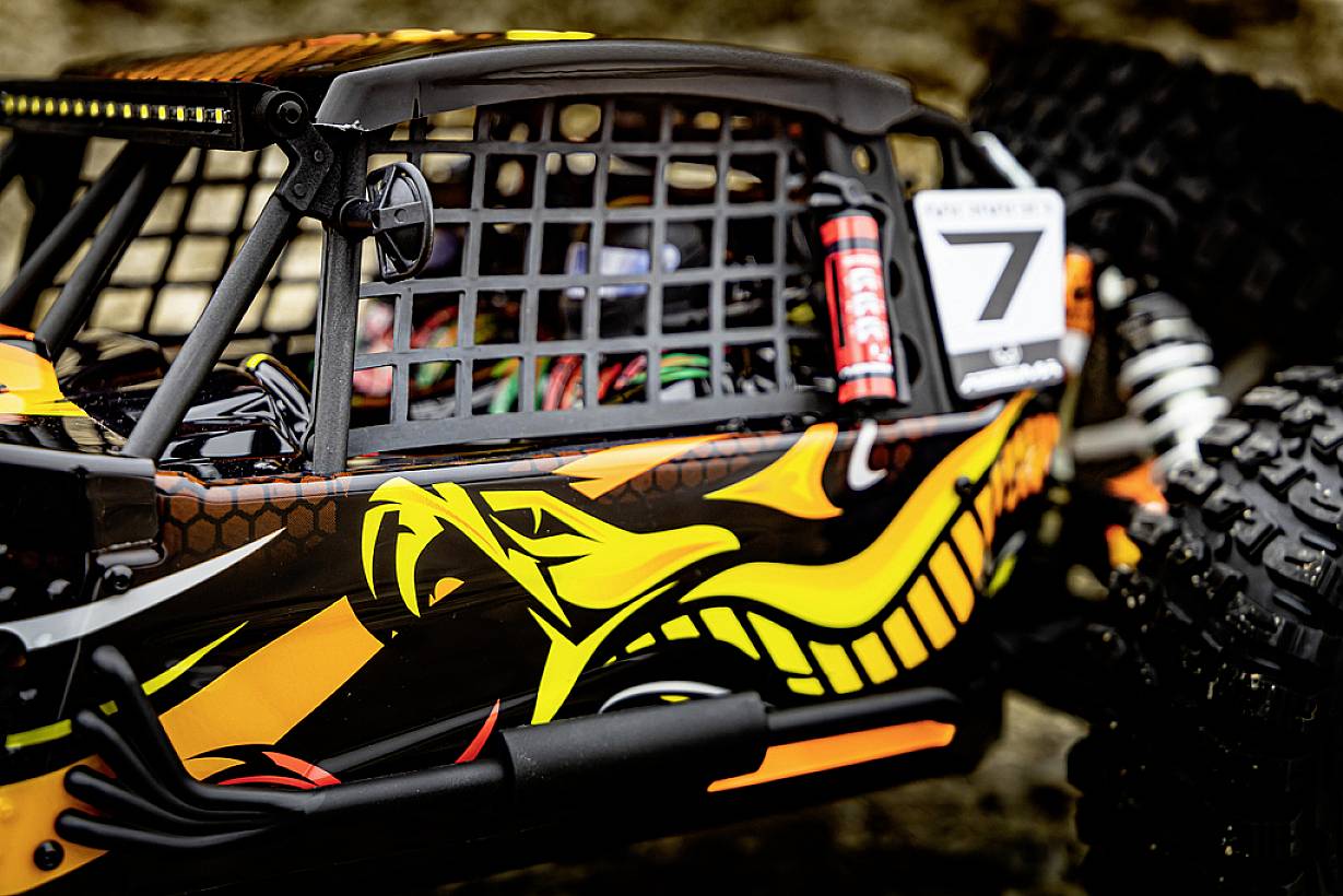 Wielobarwnie pomalowany samochód terenowy z numerem '7', kratką wlotu powietrza i grubymi oponami, przystosowany do rajdów terenowych.