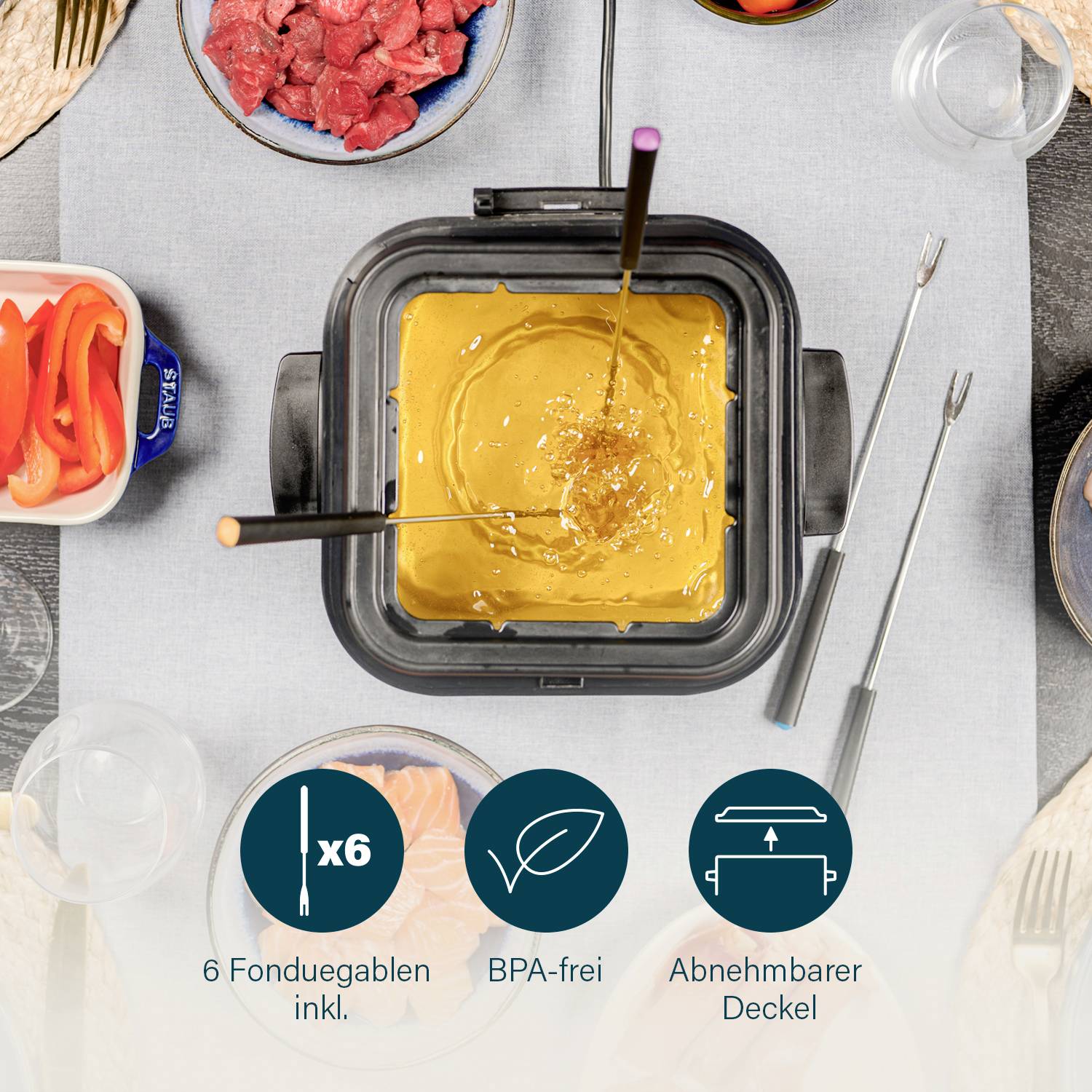 Zestaw do fondue na stole z roztopionym serem, sześć widelców wokół garnka. Wolny od BPA, zdejmowana pokrywka, czerwona papryka i mięso jako dodatki.