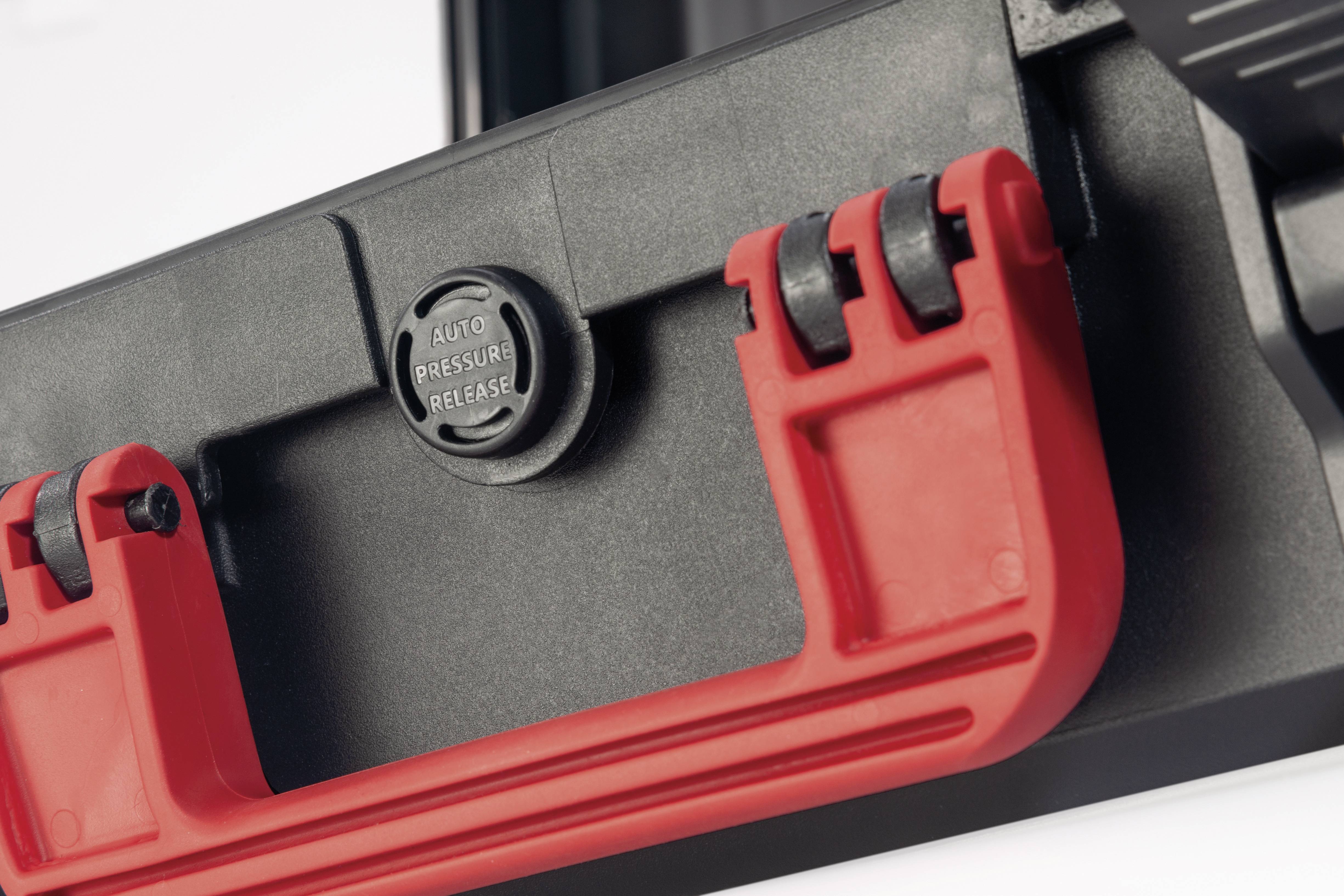 Czarny kufer z czerwonym uchwytem i przyciskiem z napisem 'Auto Pressure Release'.