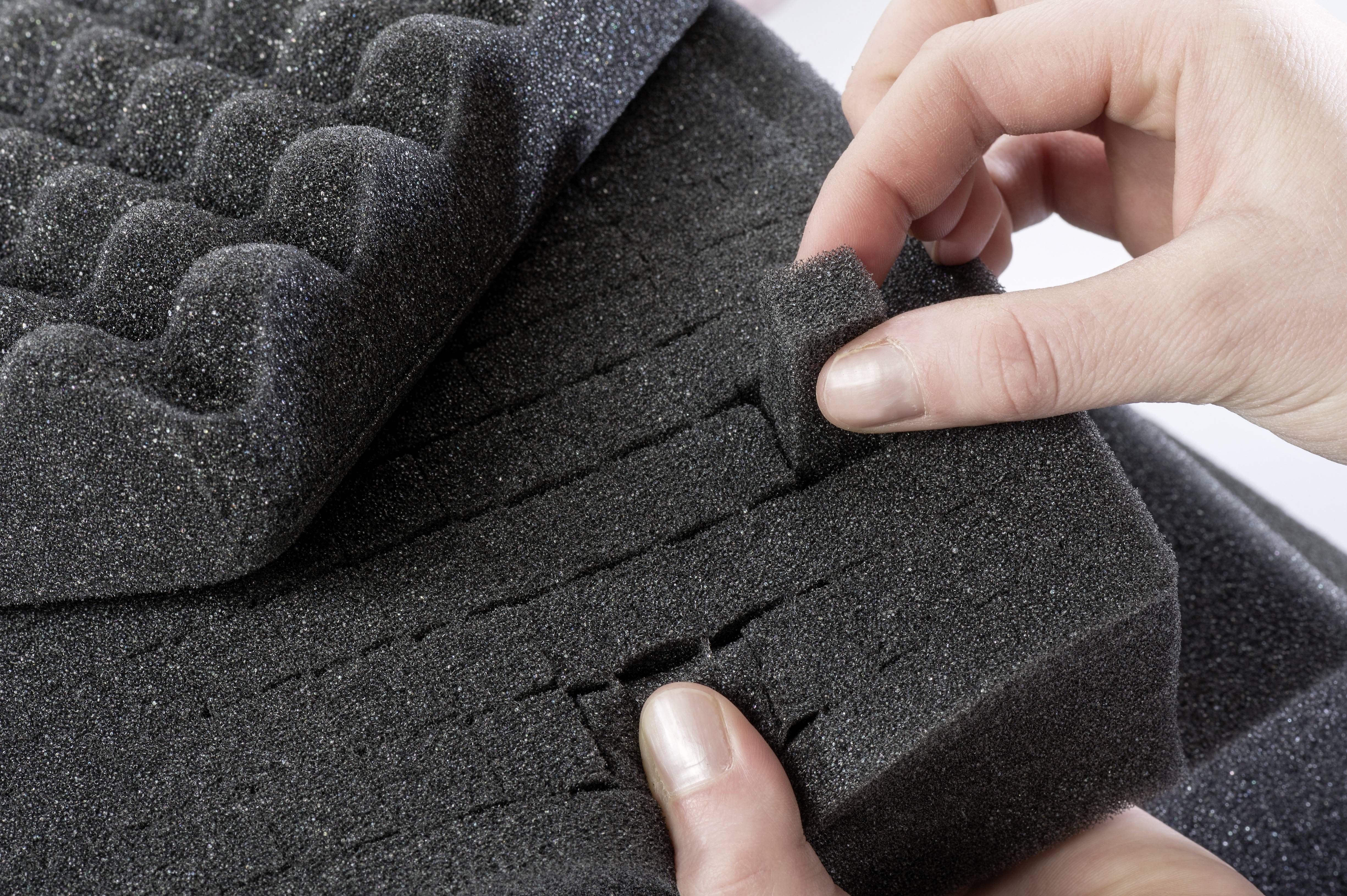 Osoba mocuje piankę akustyczną, dopasowując mały kawałek pianki do większej siatki.