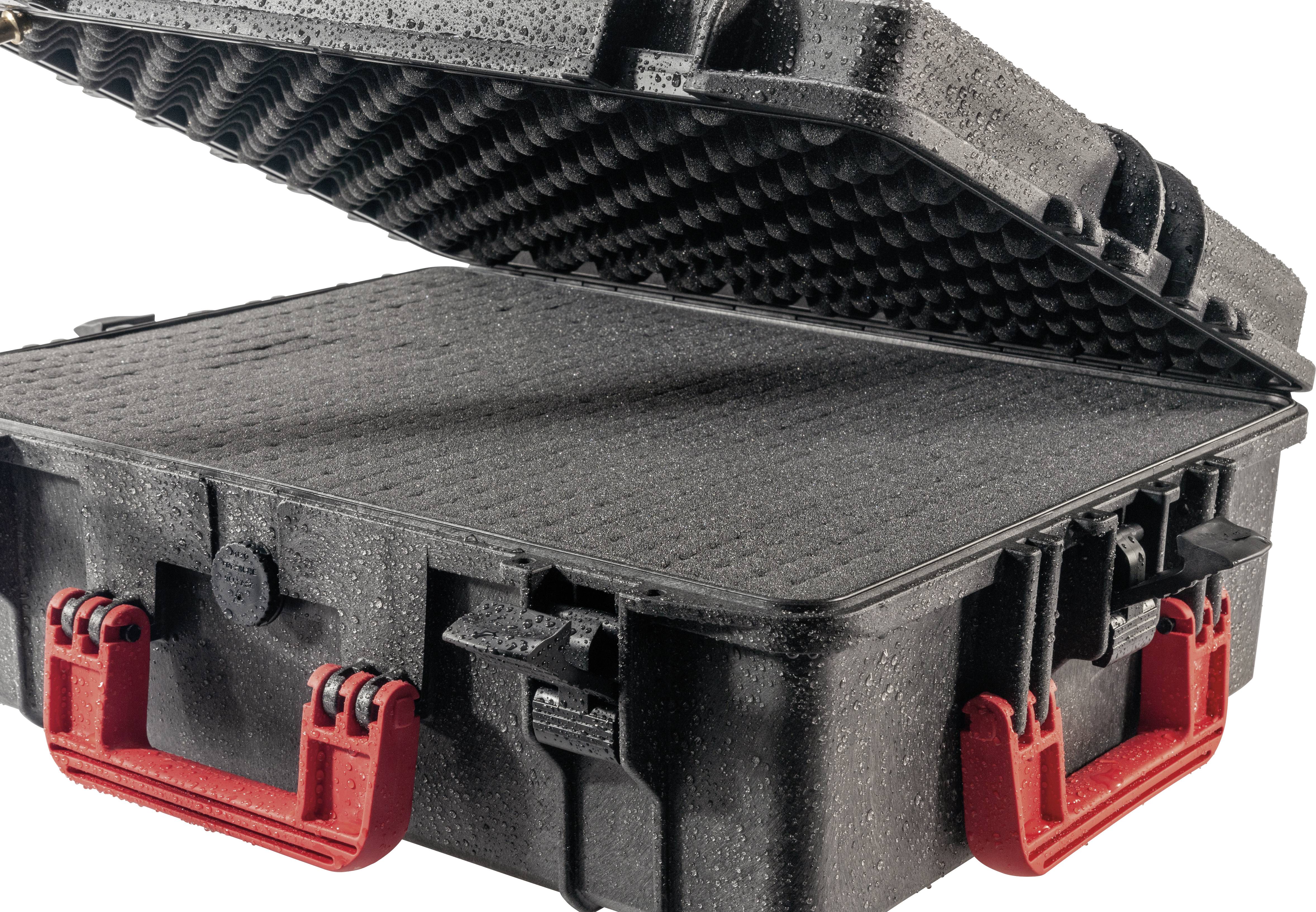Solidny czarny kufer z otwartą pokrywą i wytrzymałymi czerwonymi uchwytami. Wnętrze wyłożone jest pianką.