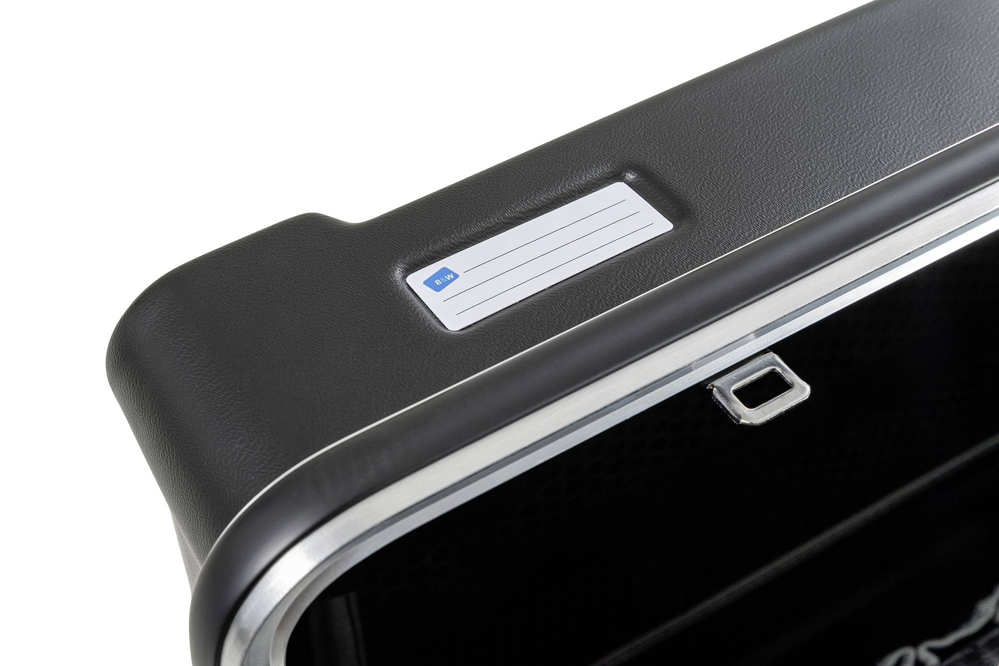 Czarny kufer z białą tabliczką z imieniem na wierzchu. Kufer posiada srebrną krawędź i małą klamrę.