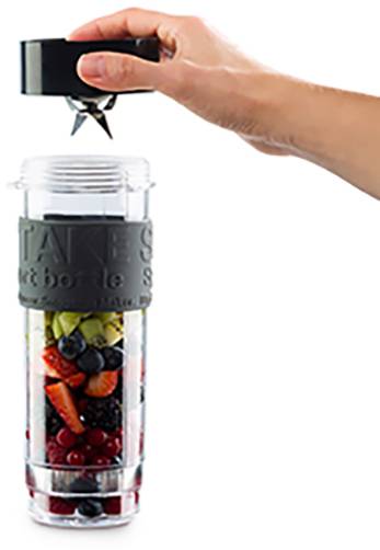 Jedna ręka trzyma blender nad pojemnikiem z warzywami i owocami, gotowa do zmiksowania.