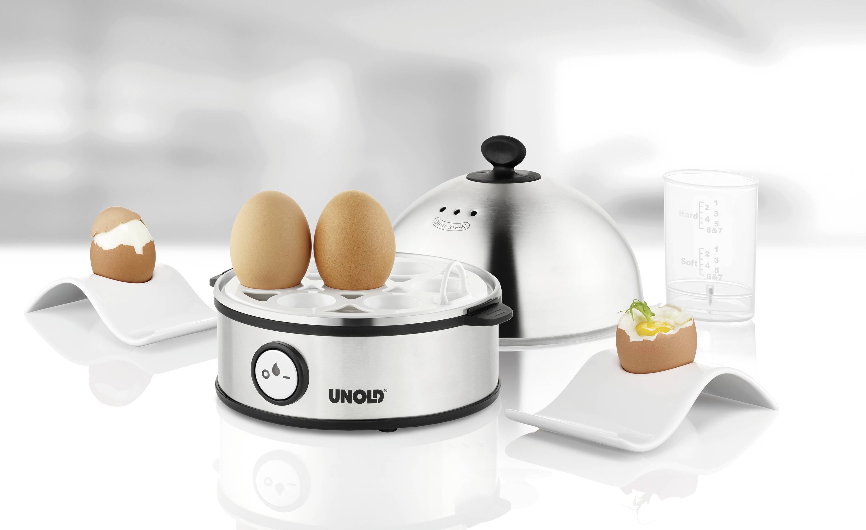 Minutnik do jajek z trzema jajkami: dwa ugotowane, jedno otwarte. Akcesoria: miarka i pokrywka ze stali nierdzewnej. Marka Unold.