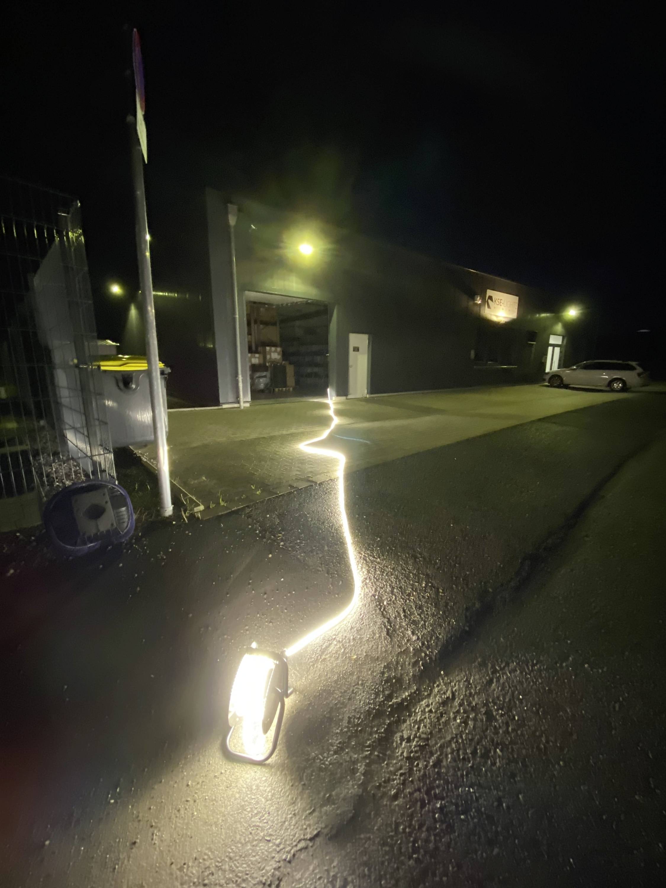 Oświetlona ścieżka prowadzi do otwartego budynku nocą. Światła na ziemi wskazują drogę i oświetlają scenę.