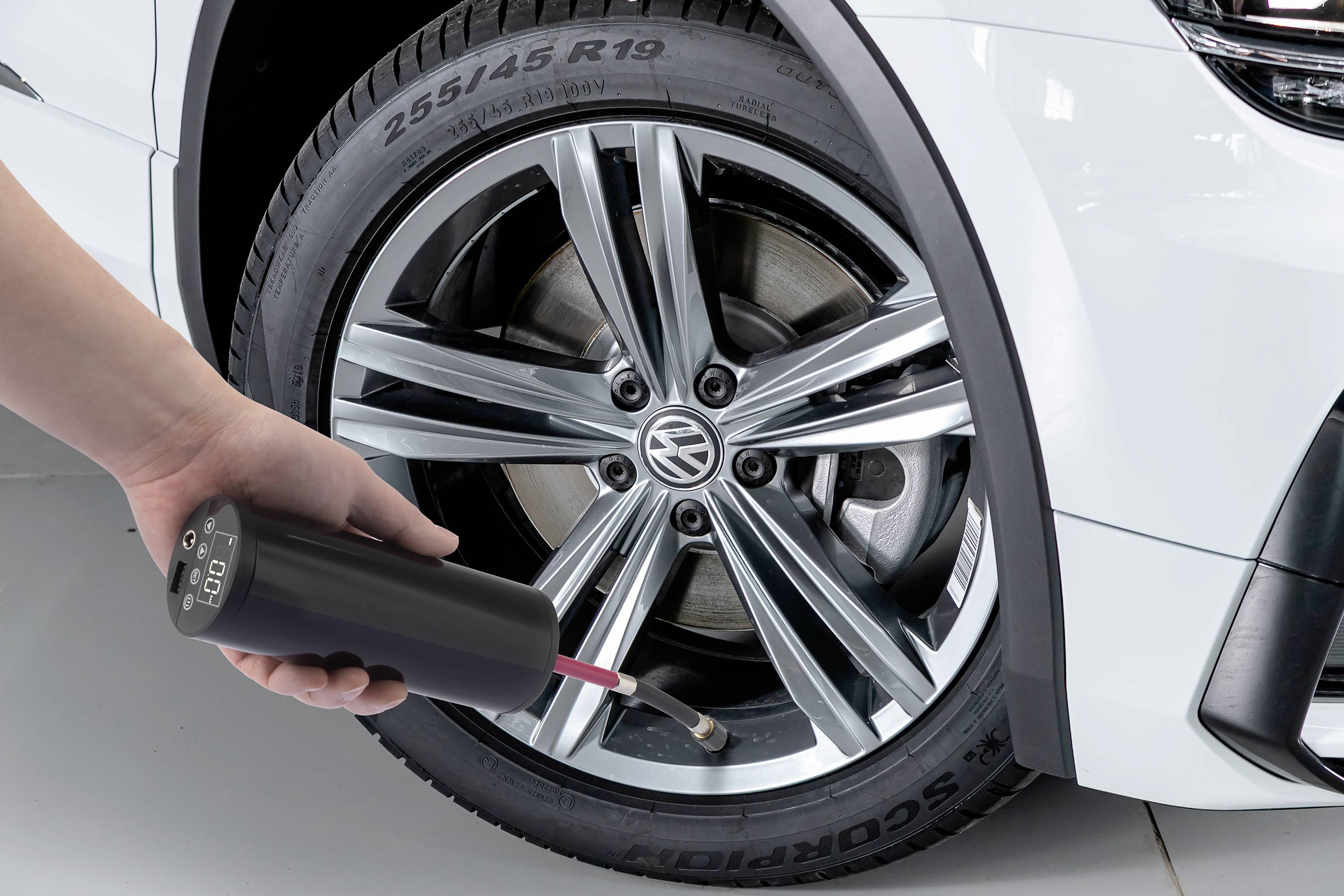 Opona samochodu jest sprawdzana pod kątem ciśnienia za pomocą elektronicznego urządzenia. Wyświetlacz pokazuje '2,5 bara'.