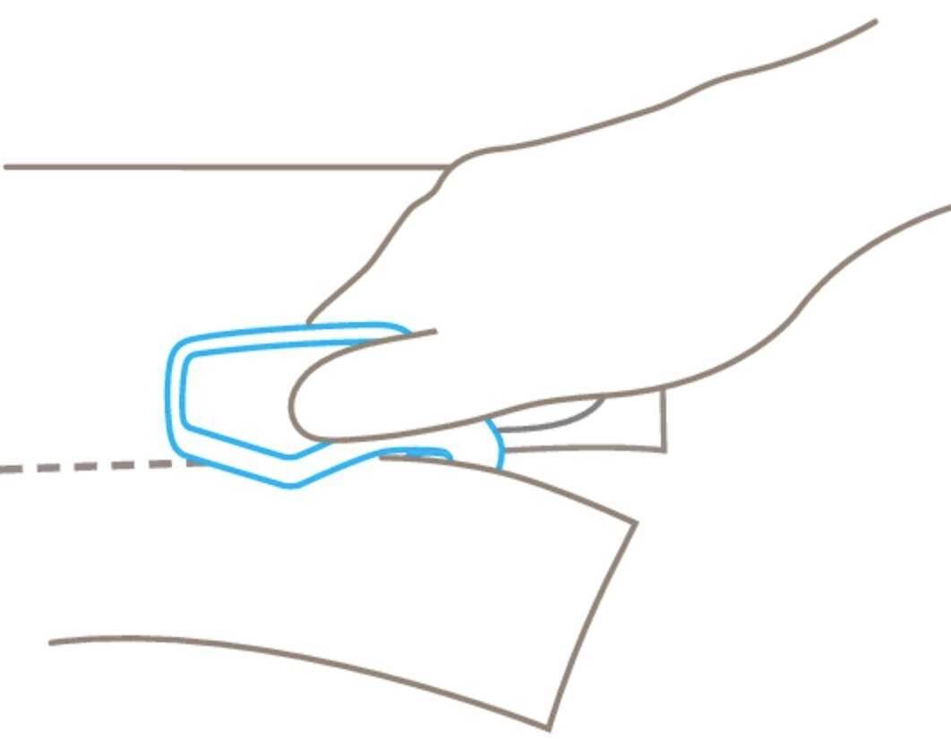 Diagram dłoni używającej trymerka do cięcia papieru wzdłuż linii przerywanej.