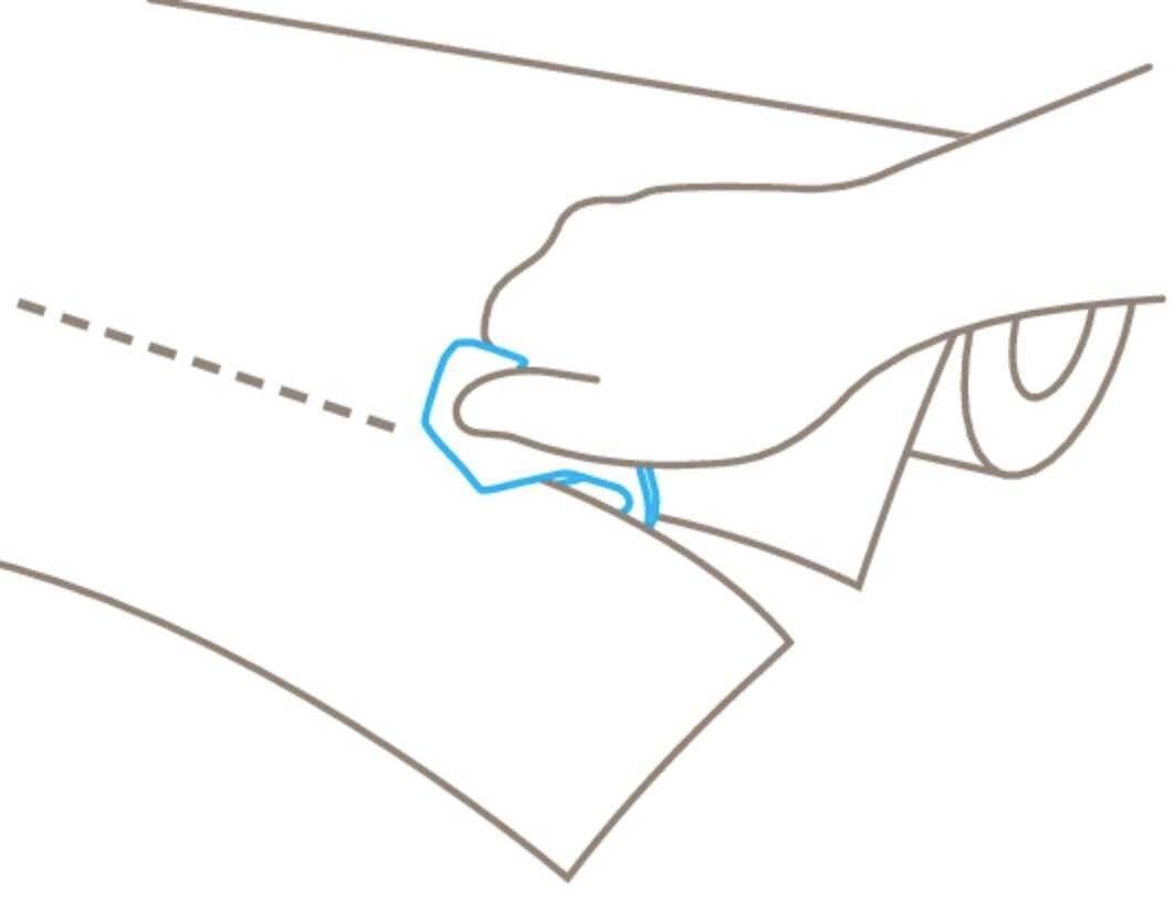 Ktoś przycina papier wzdłuż linii przerywanej za pomocą niebieskiego narzędzia tnącego.