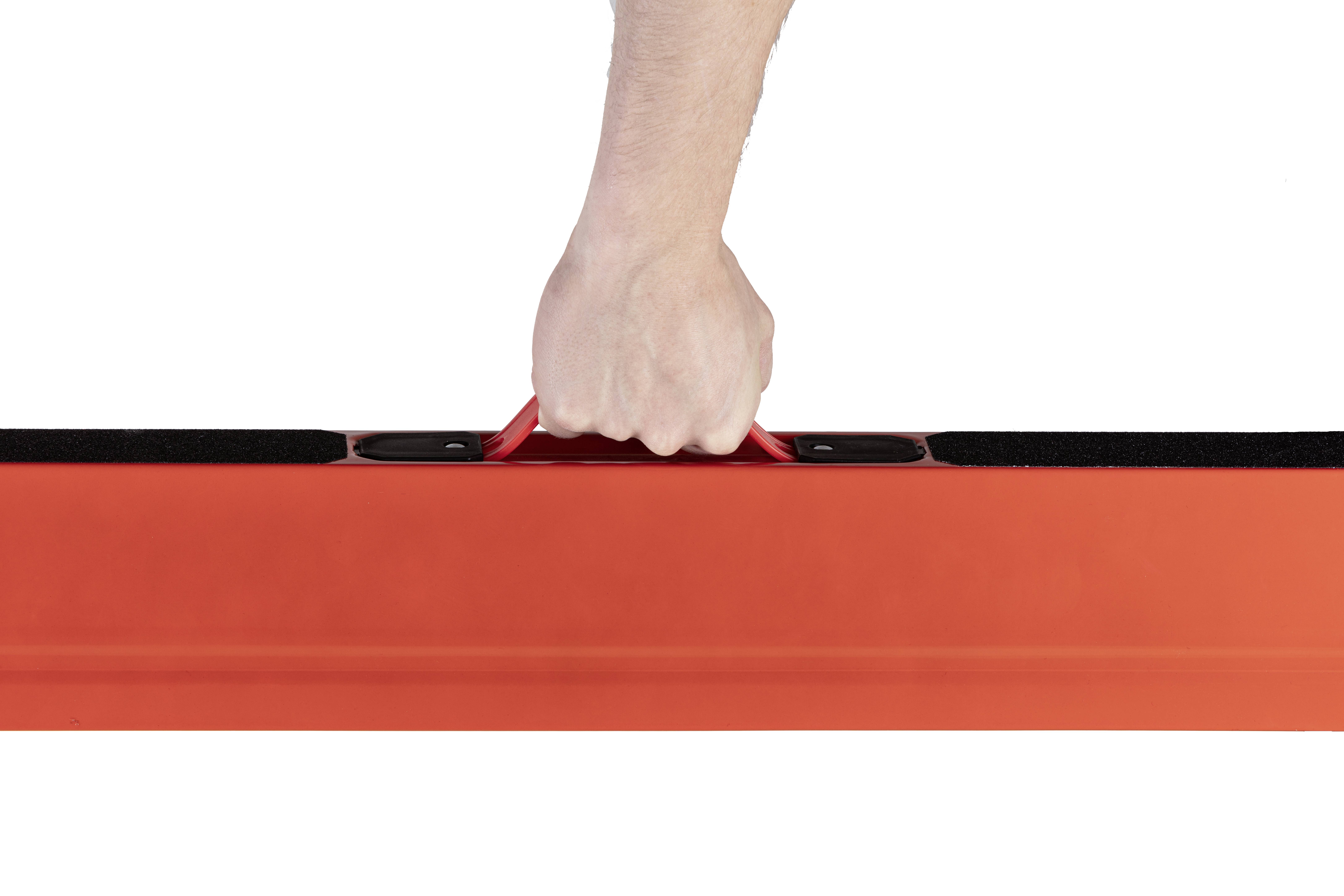 Dłoń trzyma poziomo czerwoną poziomicę, co wskazuje na jej zastosowanie podczas prac budowlanych lub majsterkowania.