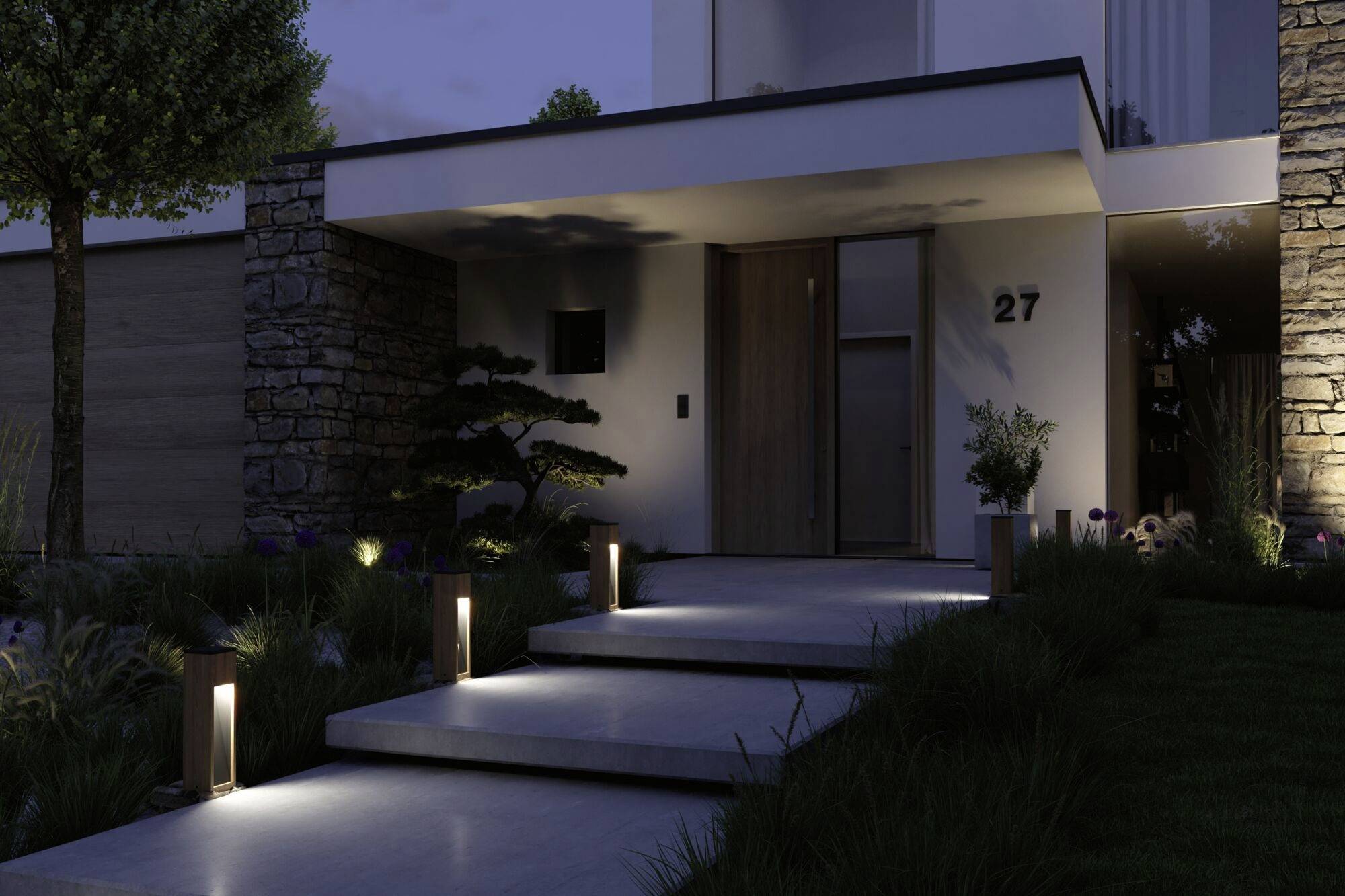 Nowoczesny dom nocą z podświetlanymi schodami i drzewem w przednim ogrodzie, o prostej architekturze i kamiennych ścianach.