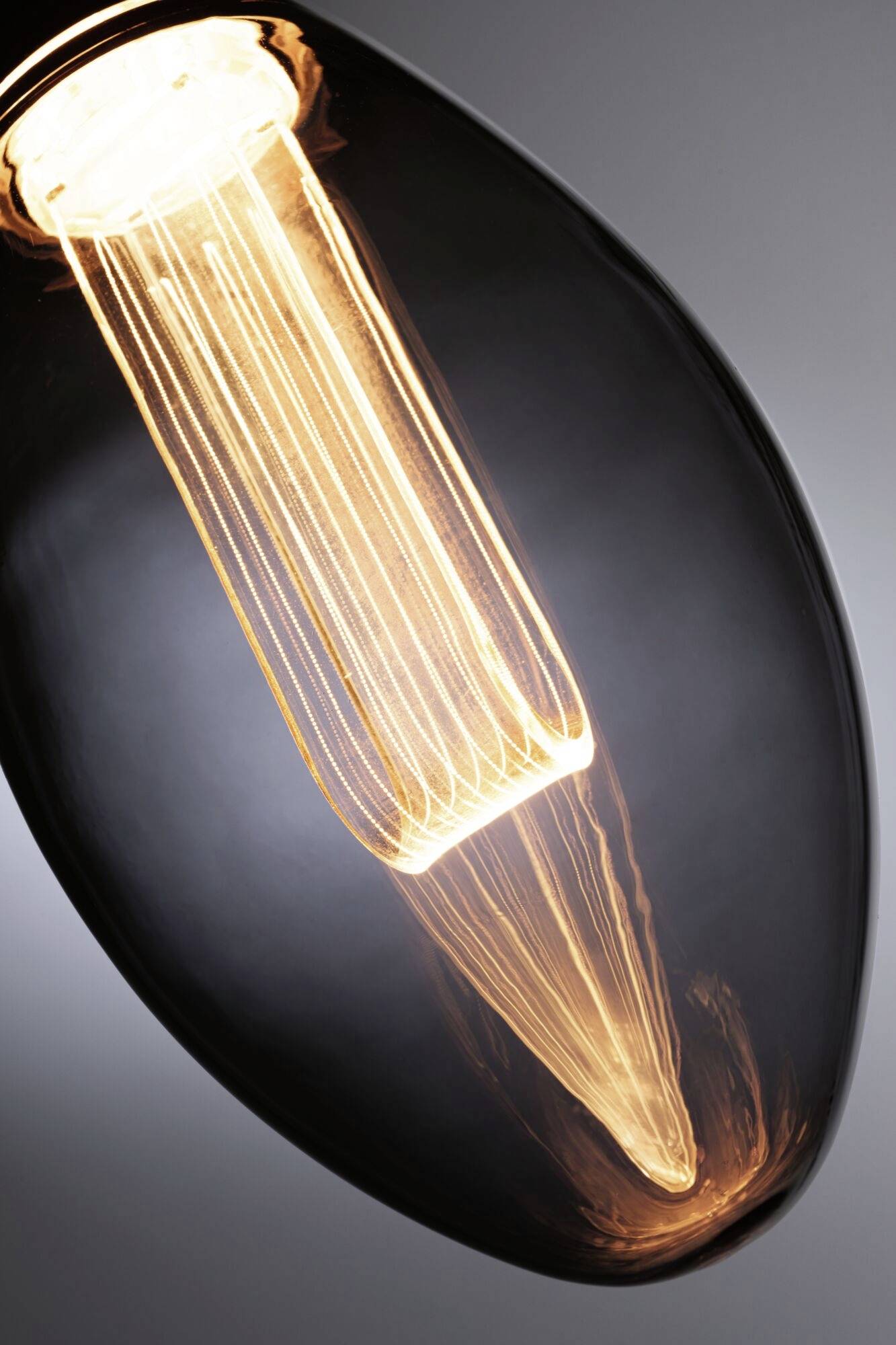 Zbliżenie świecącej żarówki z widocznymi włóknami w ciemnym pomieszczeniu.