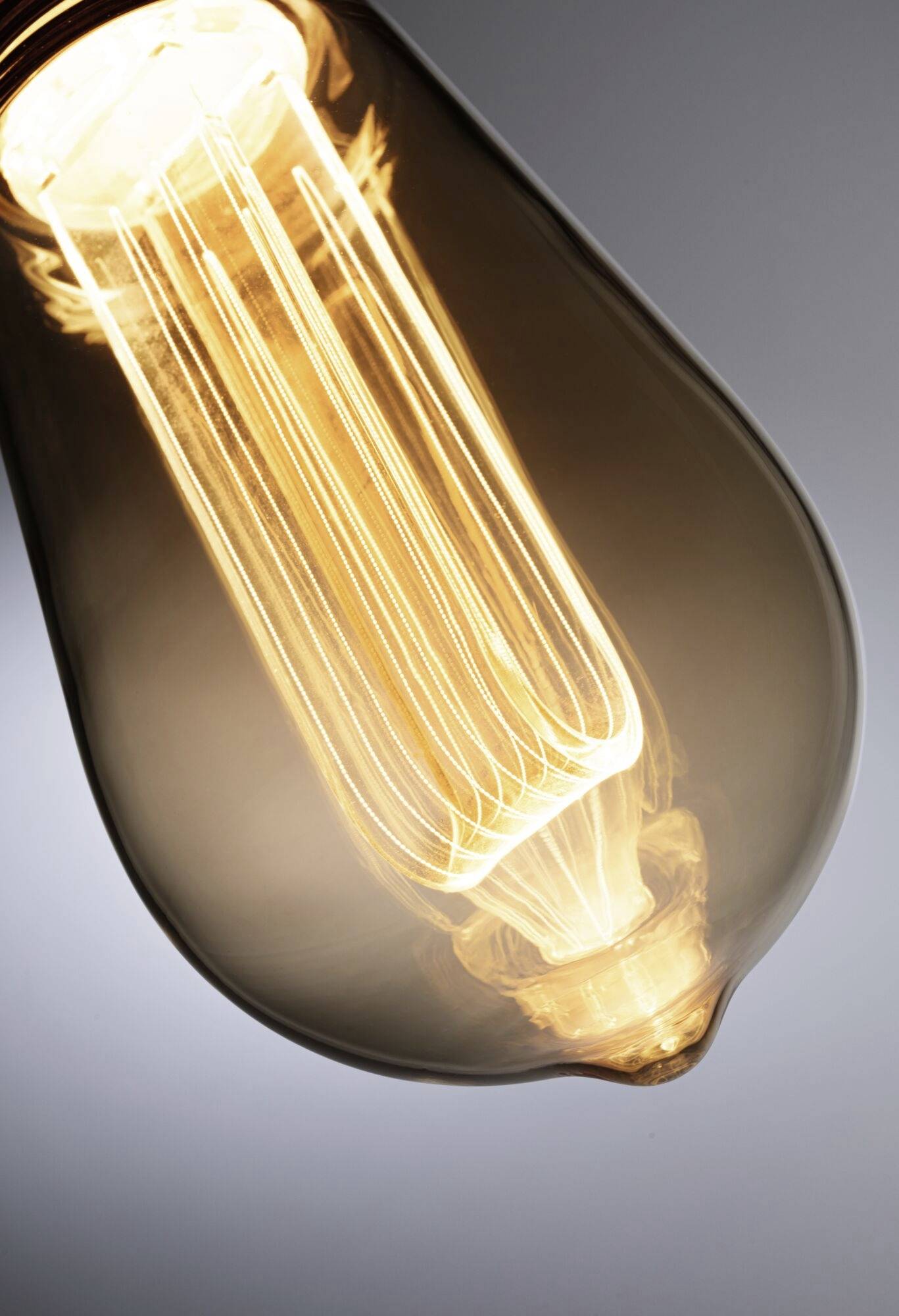 Włączona żarówka z widoczną żarówką emituje ciepłe światło.