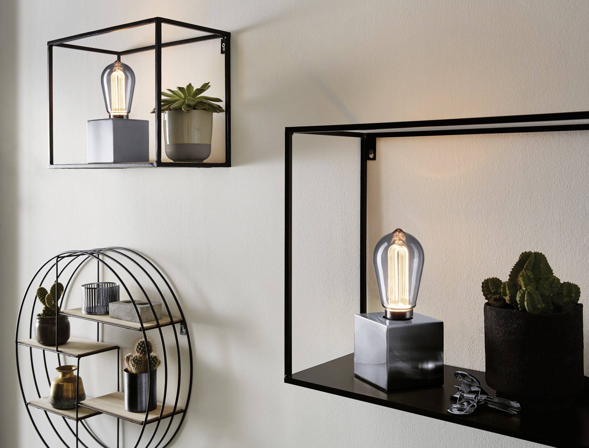 Regały z dekoracyjnymi lampami i roślinami przy białej ścianie, podkreślające nowoczesny, minimalistyczny design.