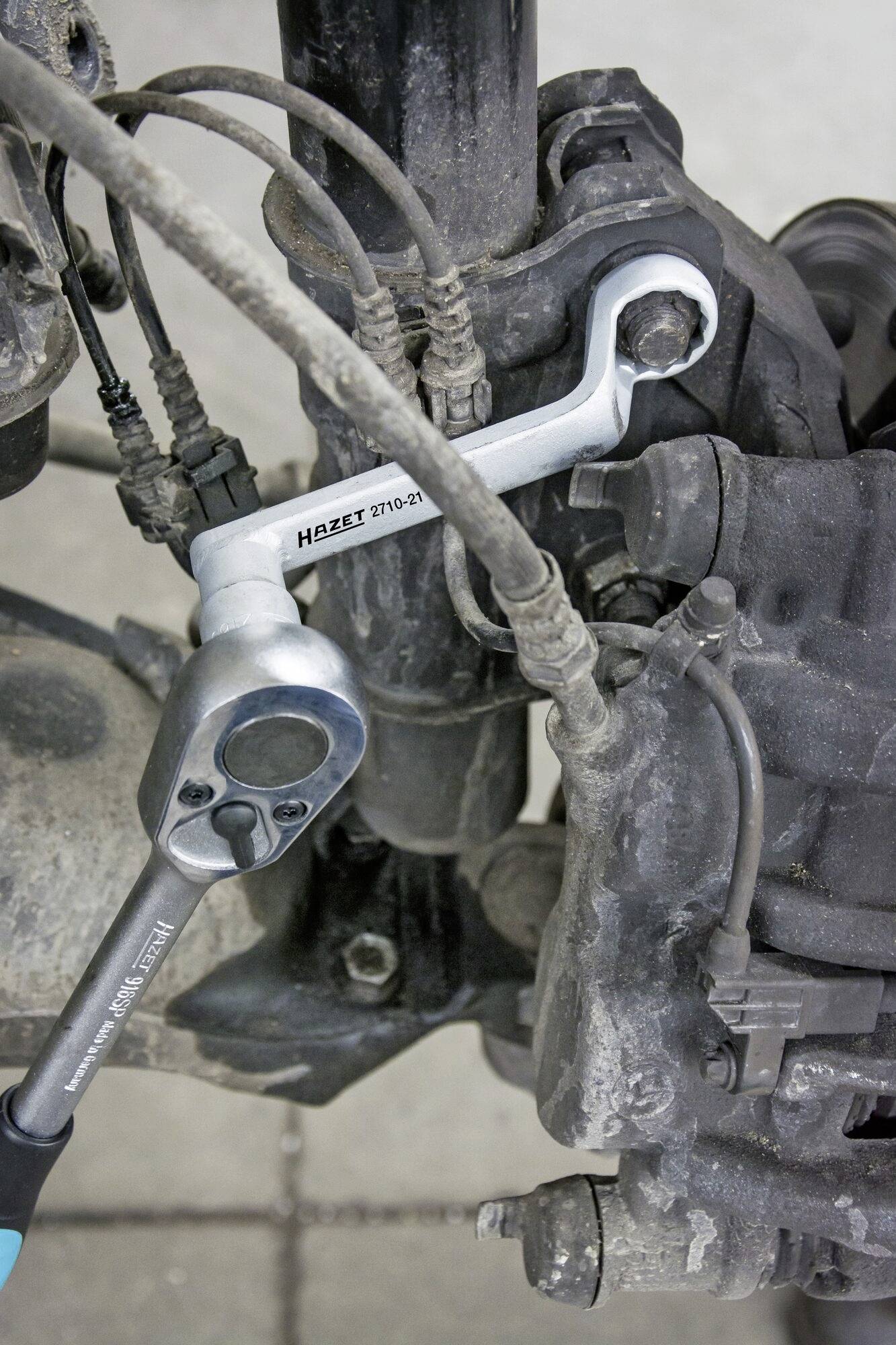 Mechanik naprawia zawieszenie samochodu, używając klucza i grzechotki do naprawy.