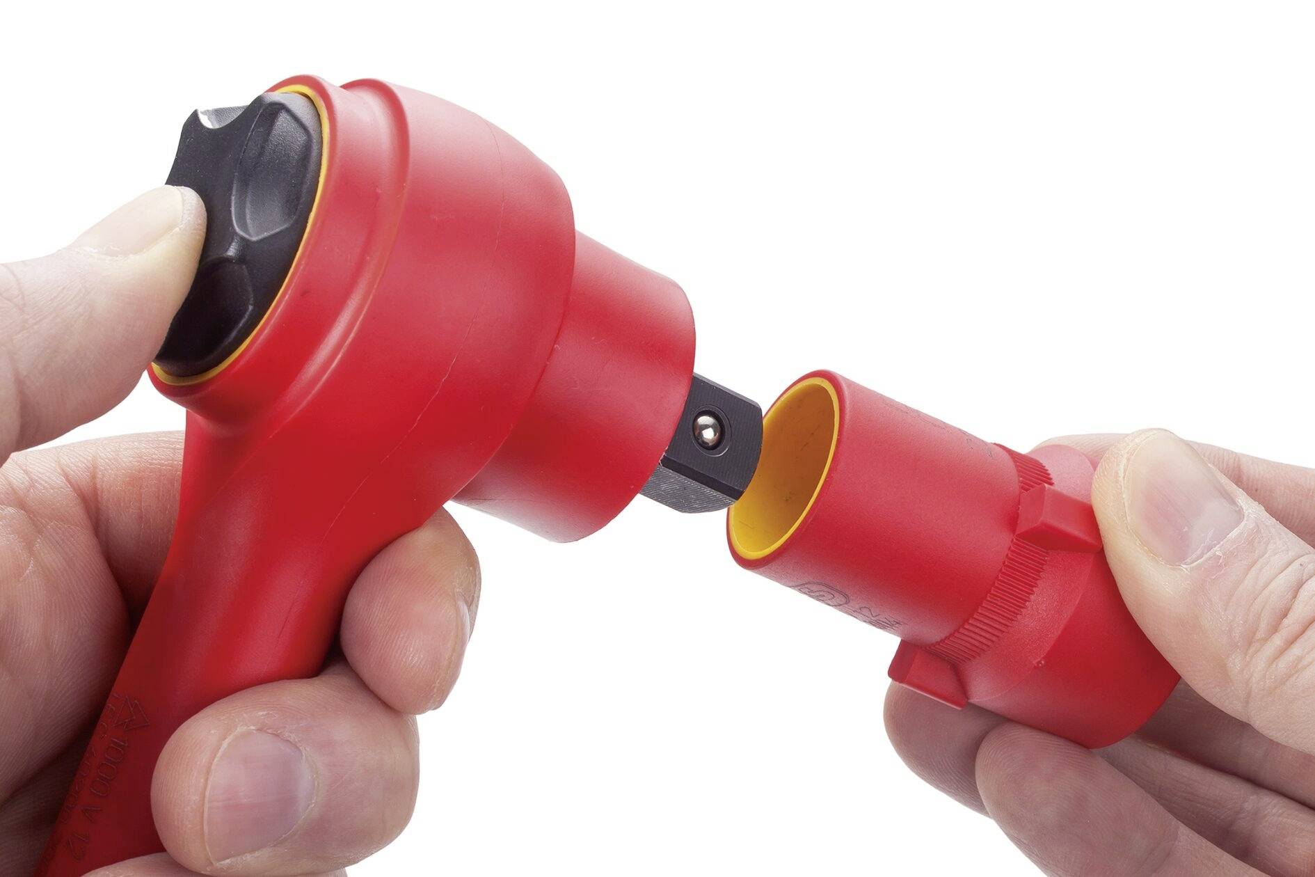 Dwie ręce trzymają czerwony uchwyt ochronny oraz czerwoną wtyczkę, która jest włożona do uchwytu. Fokus jest skierowany na połączenie elektryczne.