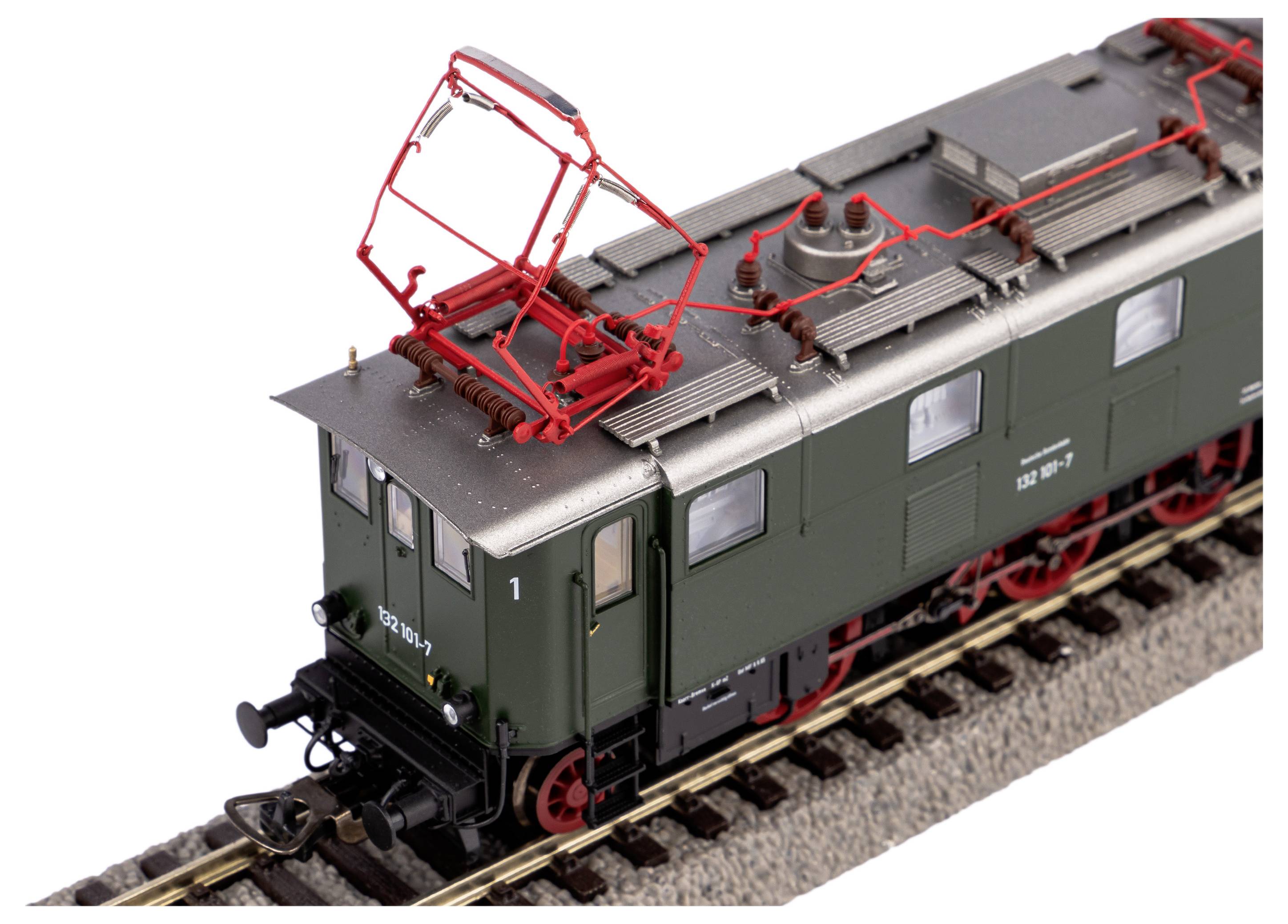 Kolejka modelarska: Zielona lokomotywa elektryczna na torze z czerwonymi przewodami trakcyjnymi i szczegółowym wykończeniem.