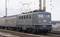 Ciemnozielona lokomotywa Deutsche Bahn ciągnie stary pociąg pasażerski po torach. W tle widoczne są linie elektroenergetyczne.