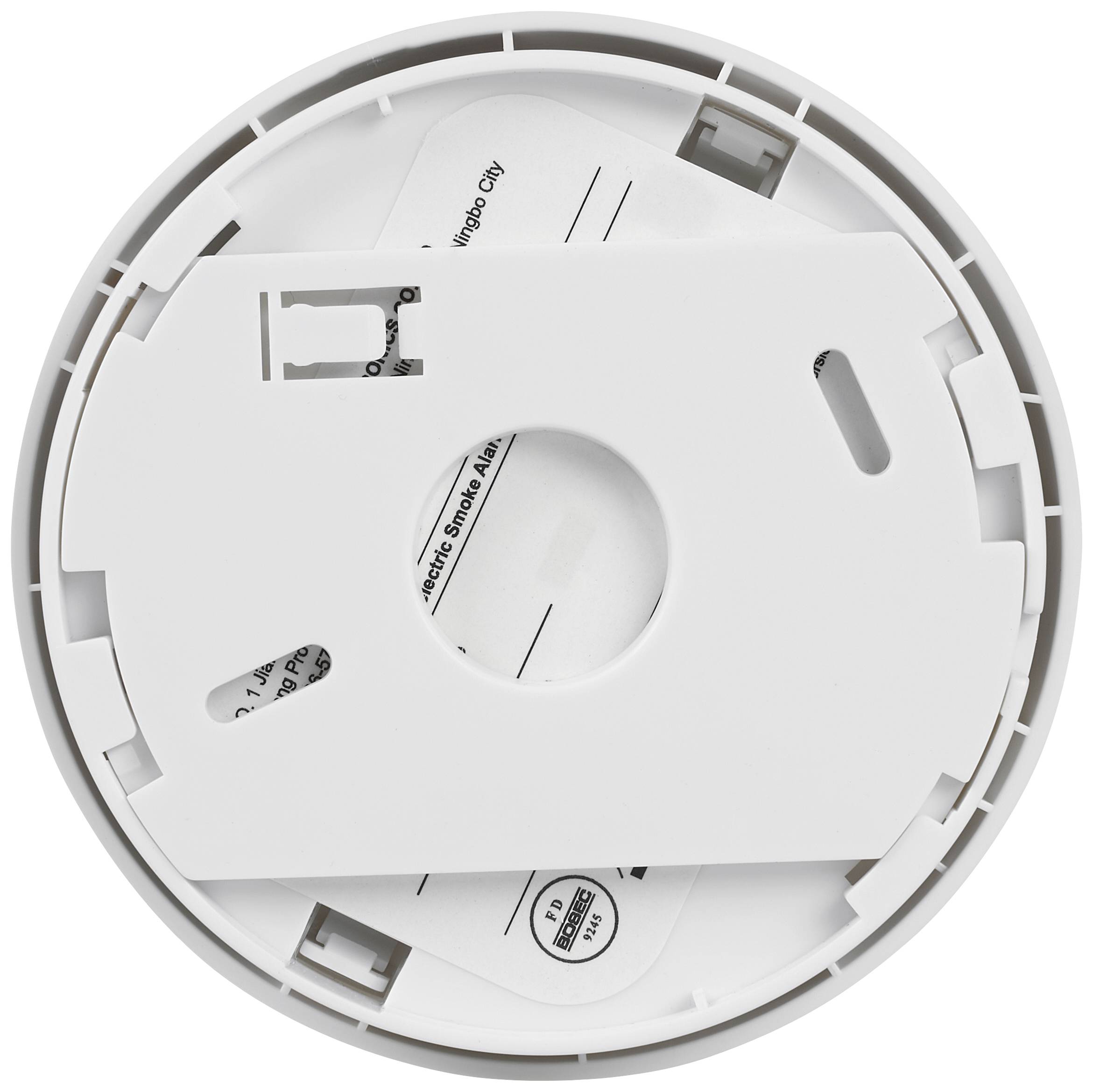 Tylna strona okrągłego czujnika dymu, z widoczną komorą baterii i instrukcją montażu.