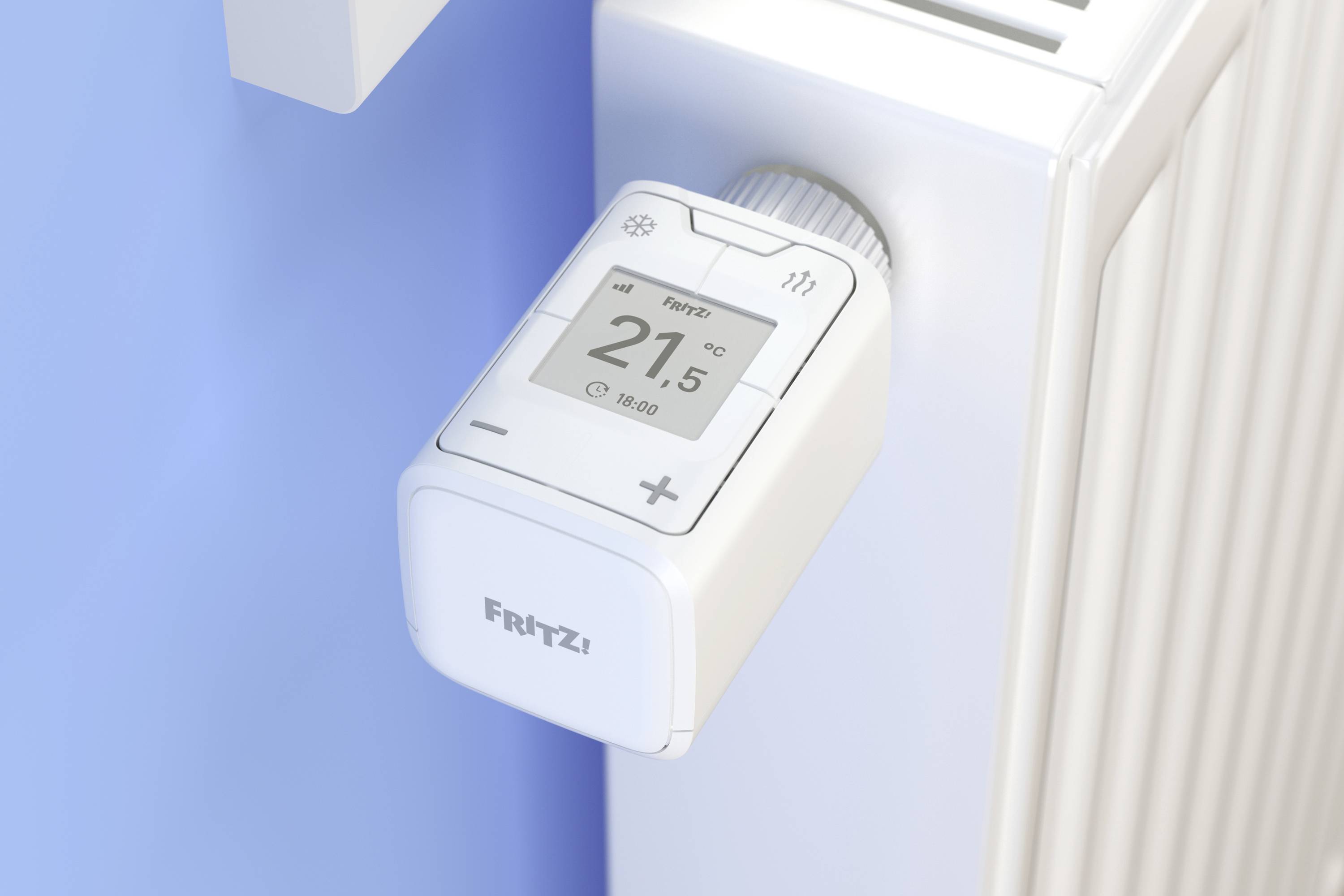 Cyfrowy termostat grzejnikowy wyświetla '21,5°C'. Jest zamontowany na białym grzejniku i obsługiwany jest za pomocą przycisku.