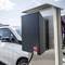 Samochód elektryczny ładuje się na stacji ładowania na parkingu. W tle widoczne są kolejne samochody i budynki.