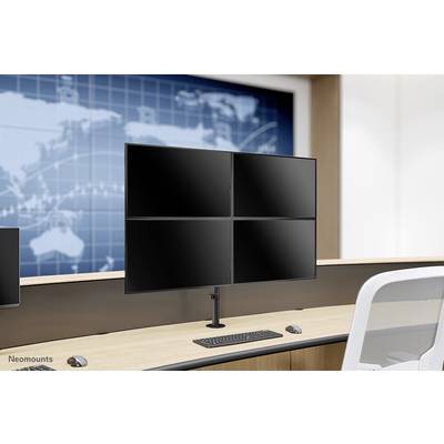 Biuro z biurkiem, na którym stoi podstawka pod monitor z czterema monitorami. Na tle ściany widać mapę świata.