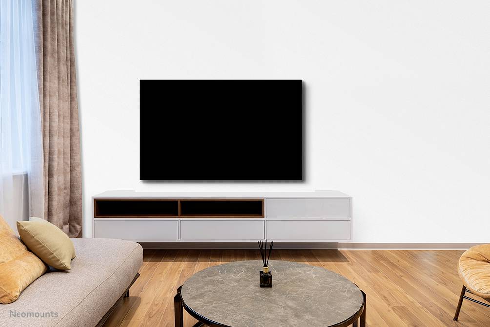 Nowoczesny salon z drewnianą podłogą, sofą, stolikiem kawowym i dużym, czarnym telewizorem zamontowanym na białej ścianie.