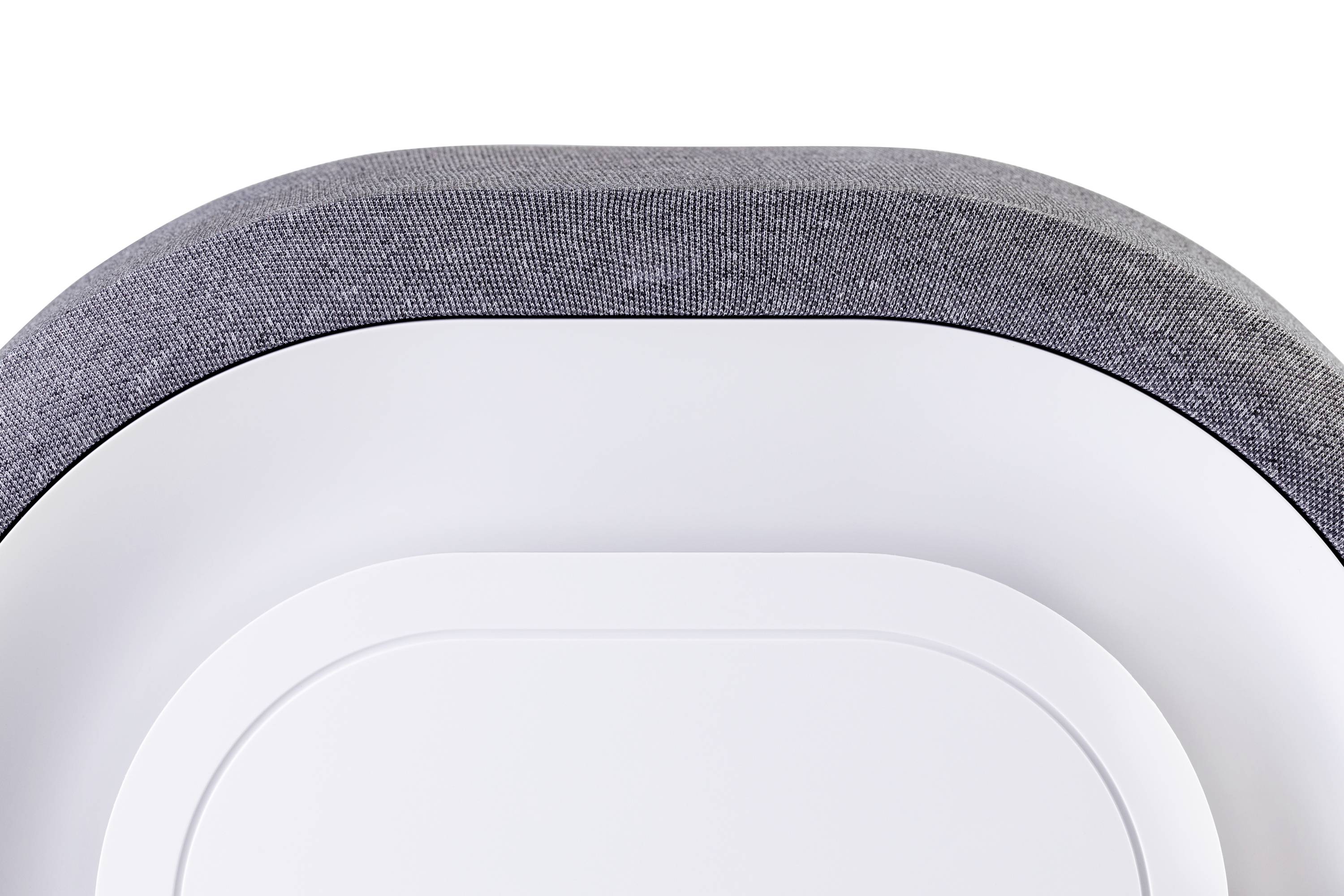 Nowoczesne, prostokątne urządzenie z zaokrąglonymi narożnikami i szarą powierzchnią tekstylną, prawdopodobnie głośnik lub inny produkt techniczny.