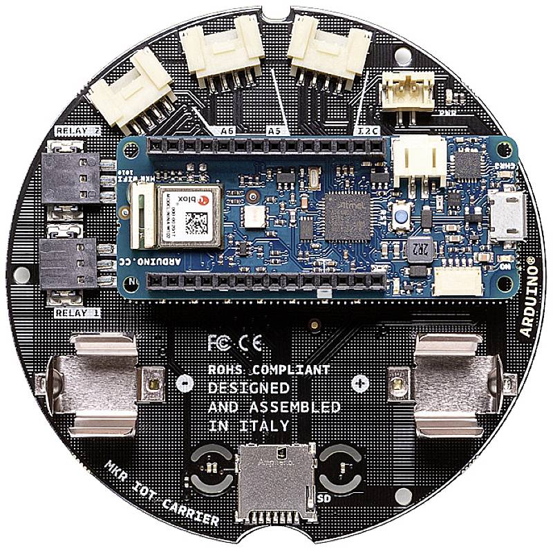 Okrągła płytka elektroniczna z różnymi złączami i centralnym, niebieskim mikrokontrolerem. Oznaczenia: 'RELAY 1', 'RELAY 2' oraz 'ARDUINO'.