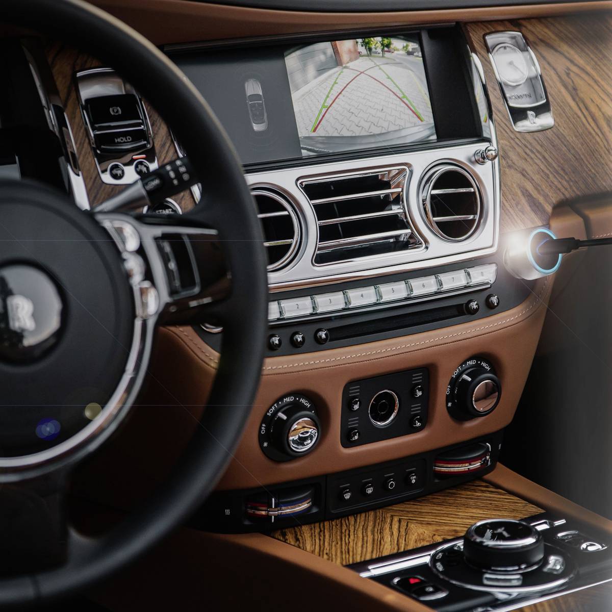 Kierownica i deska rozdzielcza luksusowego samochodu z wykończeniem drewnianym, monitor wyświetlający widok z tyłu.