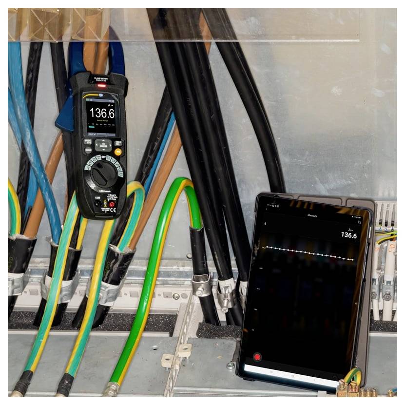 Panel elektryczny z aktywnym okablowaniem i miernikiem cęgowym pokazującym 136,6 A; tablet dubluje odczyt prądu do monitorowania.