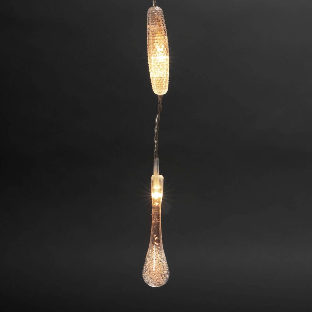 Świecąca lampa wisząca o błyszczącym designie zwisa na czarnym przewodzie na ciemnym tle.