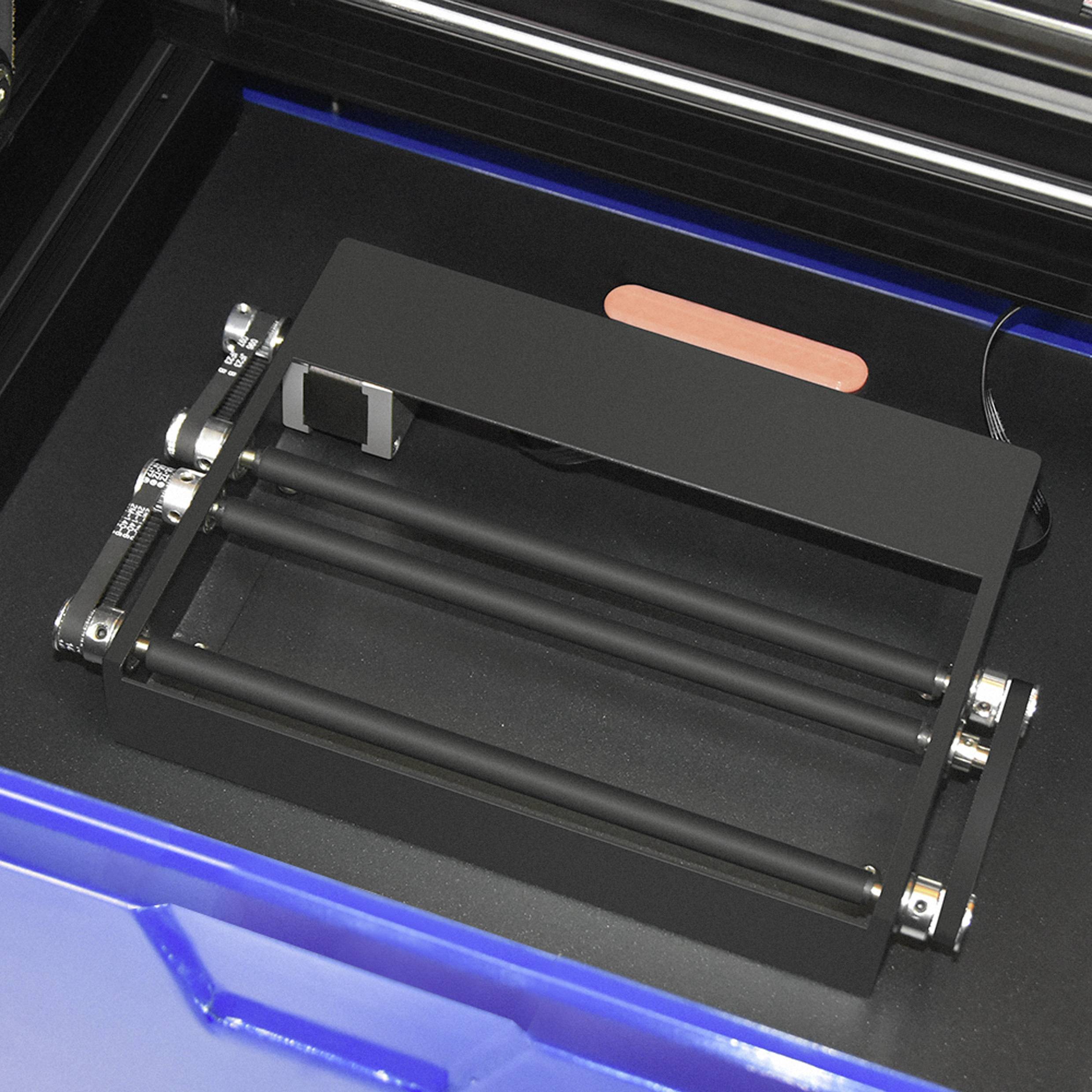 Otwarty drukarz 3D z widocznymi rolkami i platformą do podawania materiału.