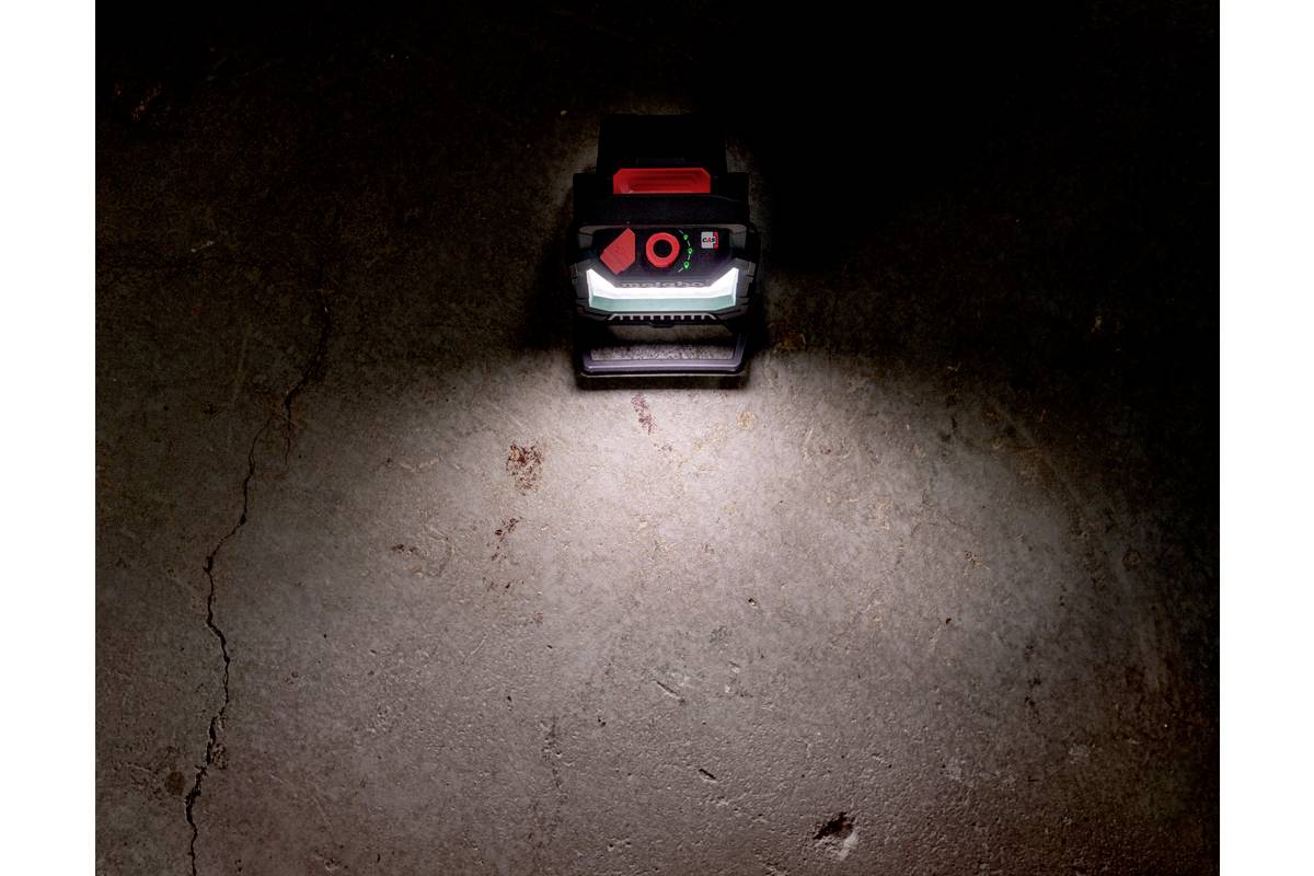 Lampa robocza leży na betonowej podłodze, świeci jasno i rozświetla bezpośrednio otaczający ją obszar.