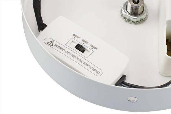 Przełącznik z napisem 'WYŁĄCZYĆ PRZED PRZEŁĄCZENIEM' do regulacji barwy światła: 3000K, 4000K, 6500K. Zamontowany w oprawie oświetleniowej.