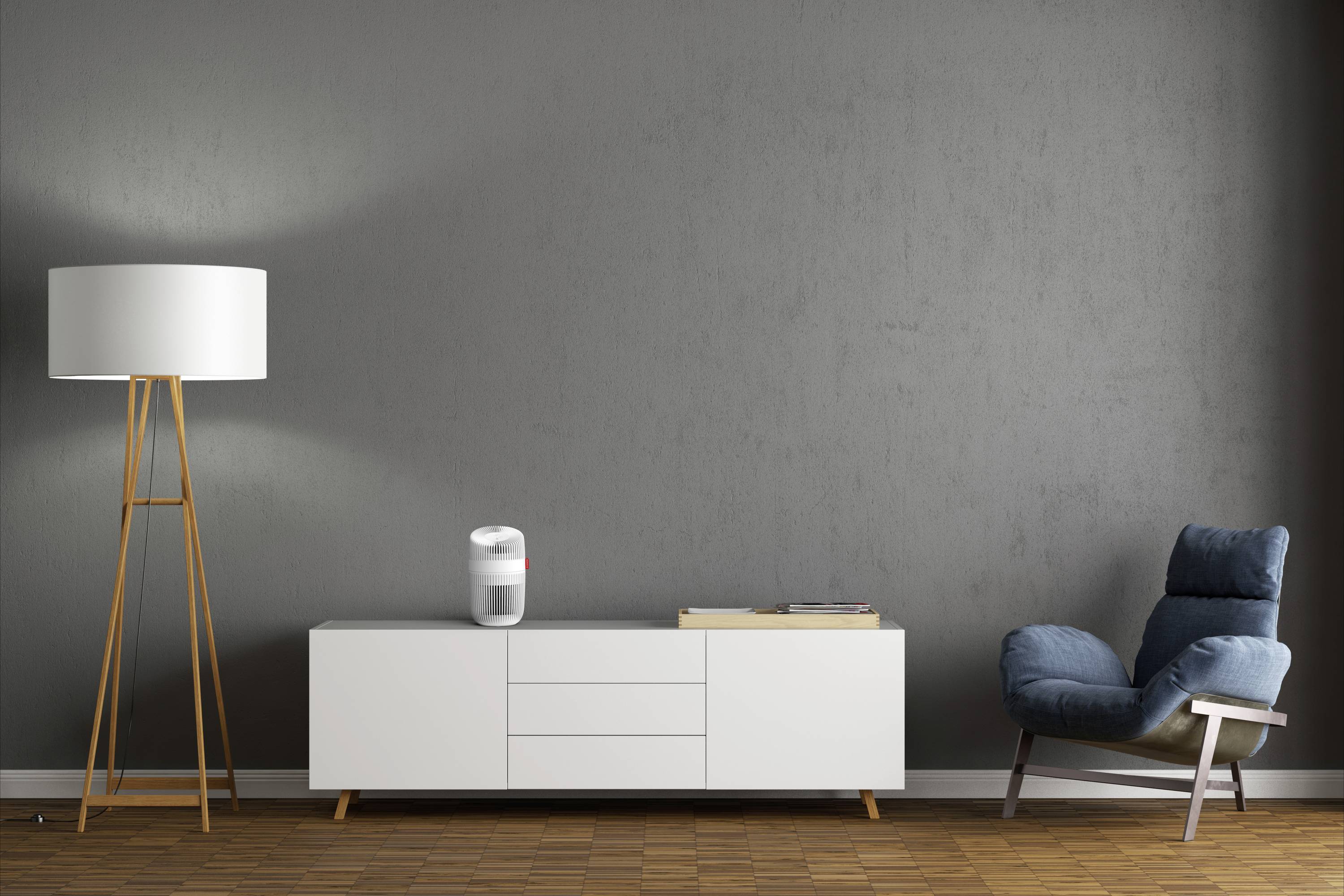 Salon z szarą ścianą, białą komodą, na której stoi inteligentny głośnik, po lewej stronie lampa stojąca, a po prawej niebieski fotel.