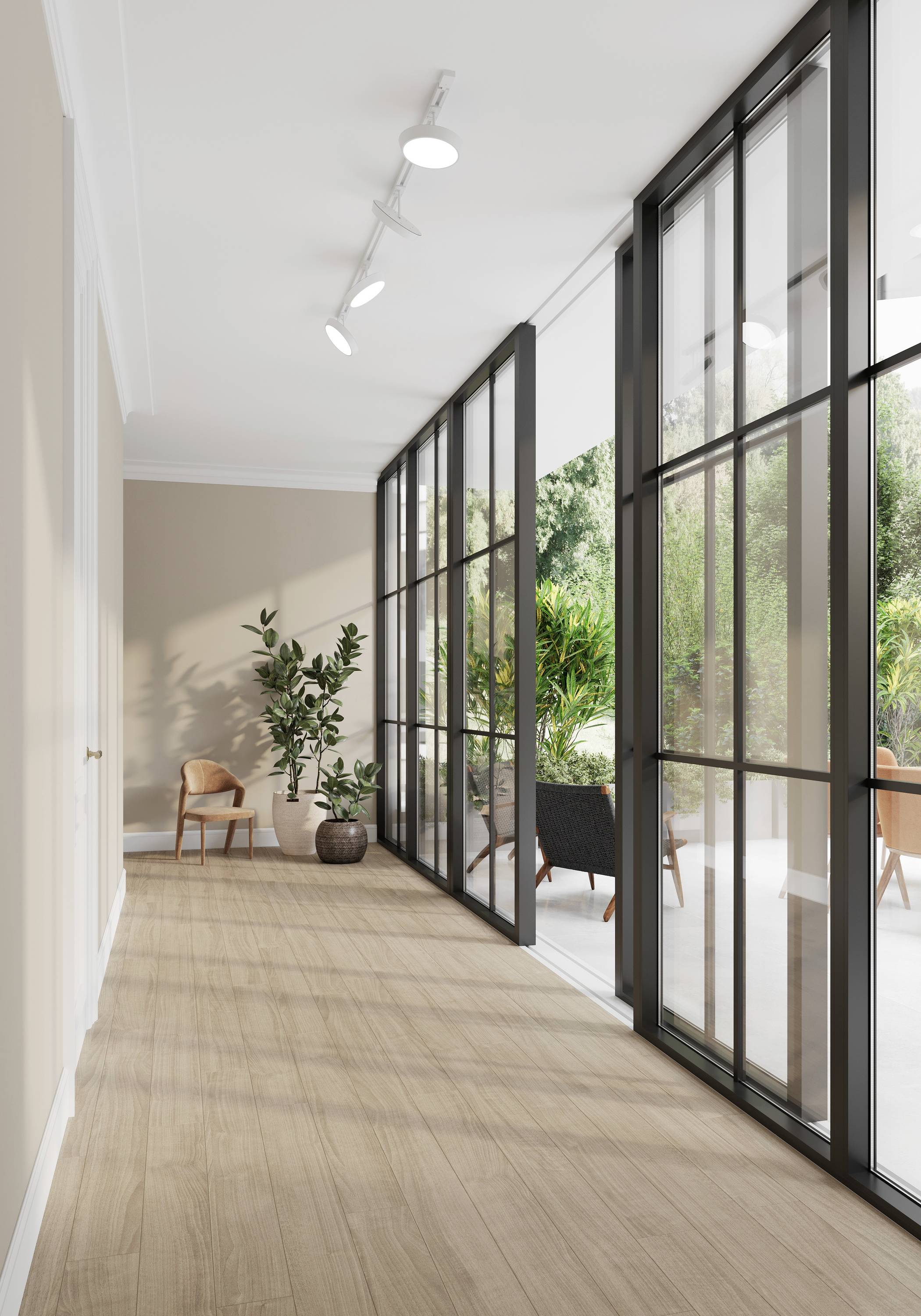Nowoczesny, jasny korytarz z drewnianą podłogą, dużymi oknami szklanymi i widokiem na zielony ogród. Widoczne są rośliny i krzesła.