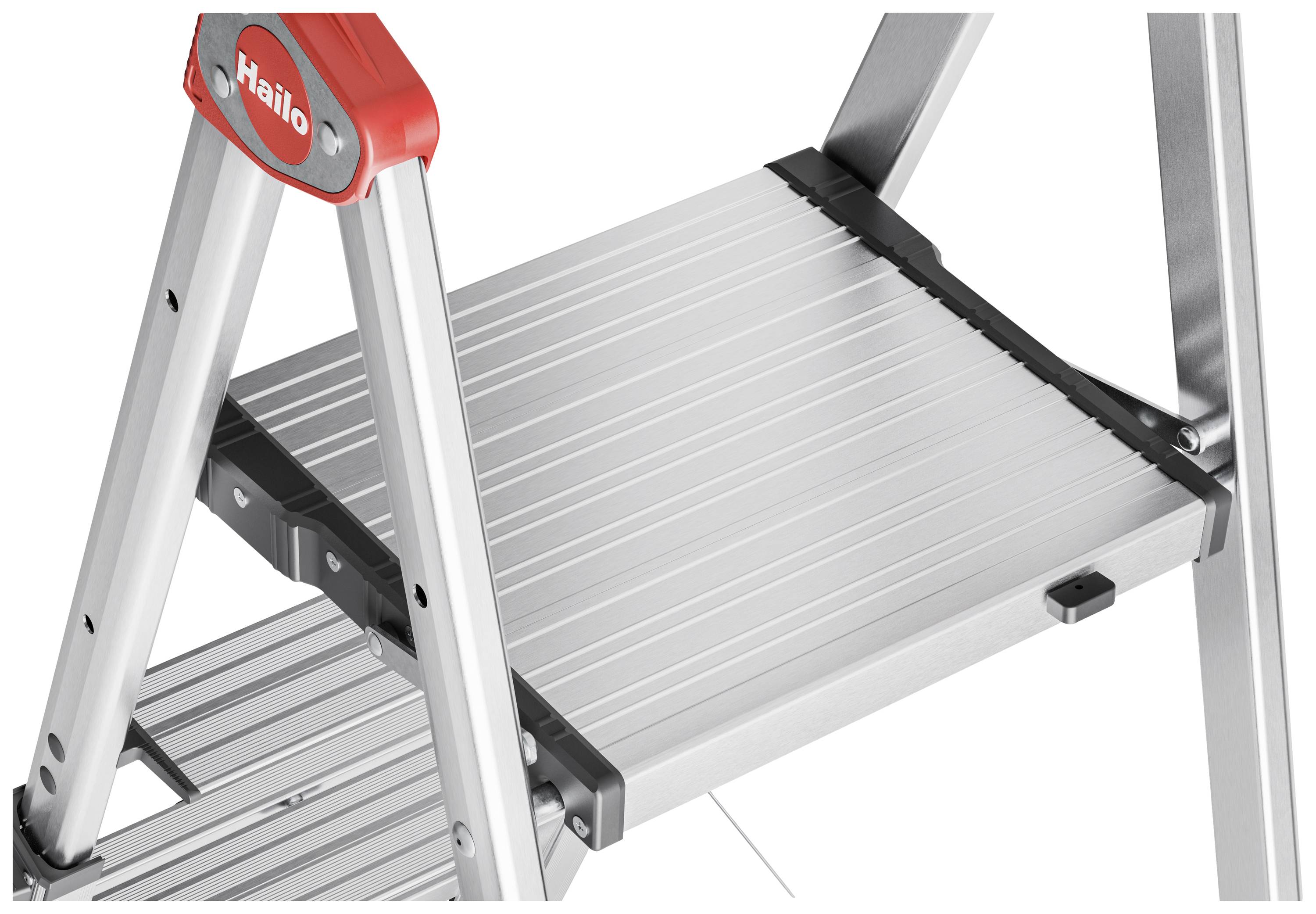 Srebrna aluminiowa drabina z szerokimi stopniami zapewniającymi stabilne podparcie, z czerwonymi akcentami na narożnikach. Idealna do użytku wewnątrz pomieszczeń.