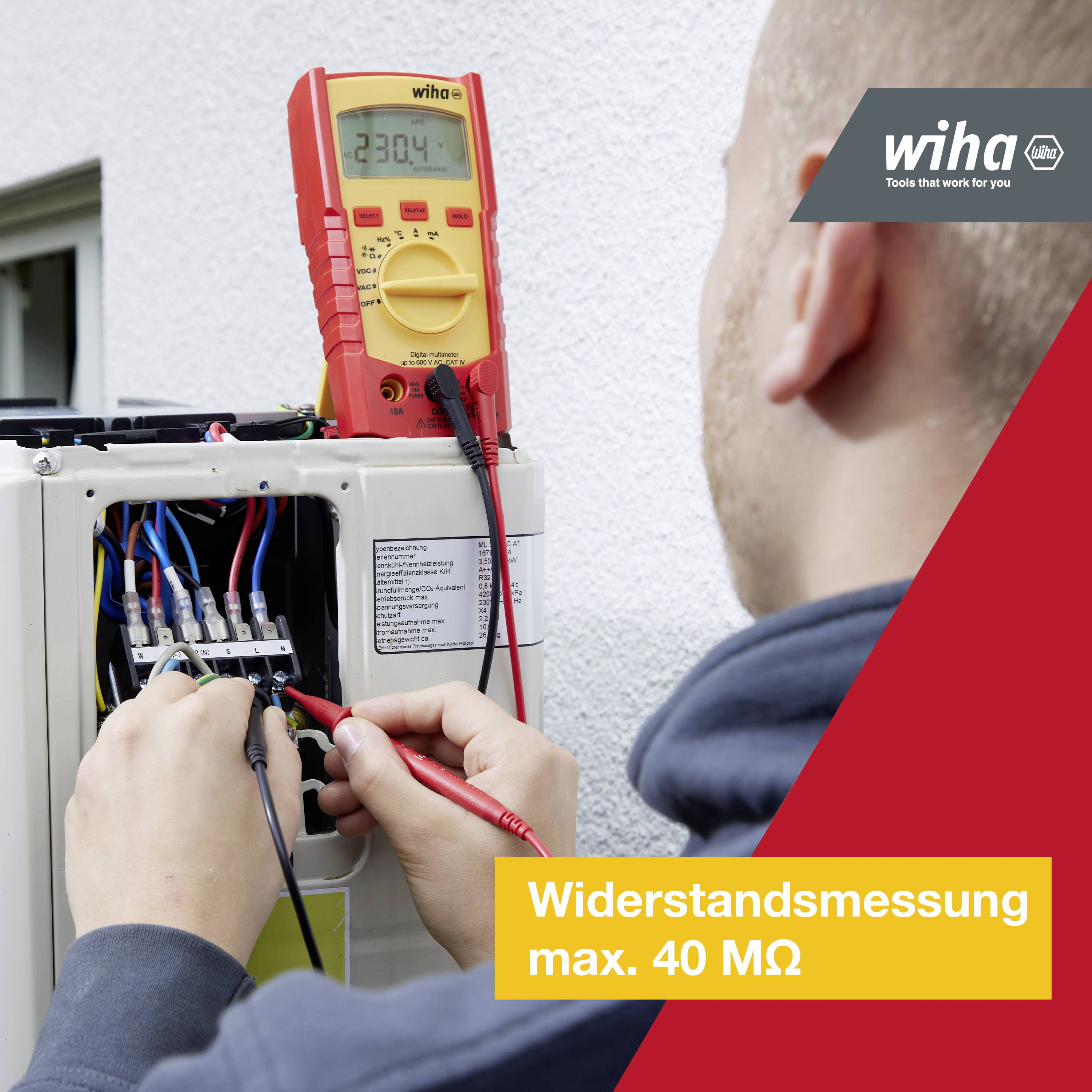 Osoba mierzy opór elektryczny w otwartej szafce rozdzielczej. Multimetr wskazuje 230,4.