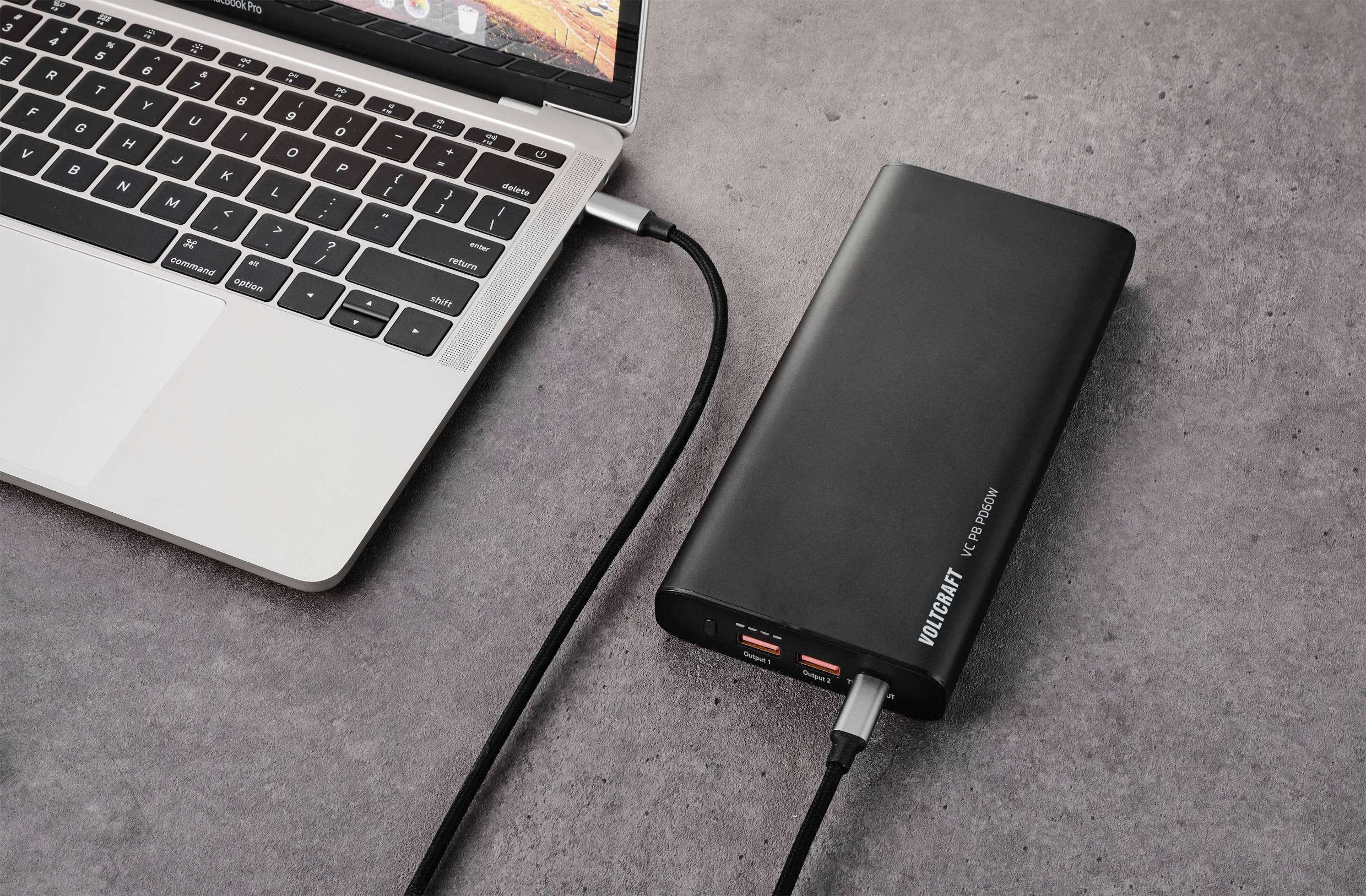 Laptop jest podłączony do przenośnej ładowarki; pokazuje korzystanie z mobilnego zasilania.