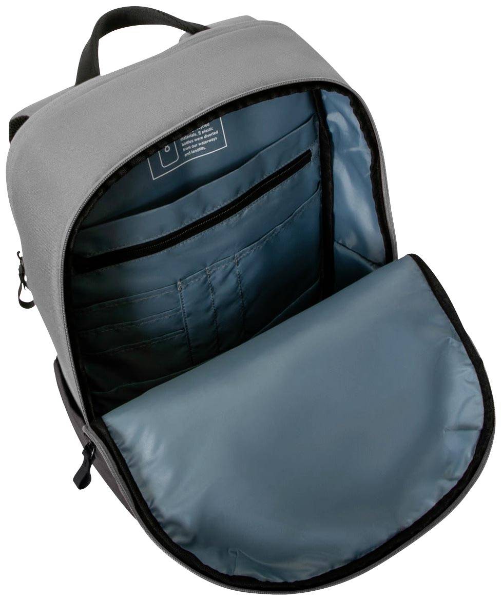 Szary plecak jest szeroko rozłożony, ukazując kilka kieszeni oraz dużą komorę główną z niebieską podszewką wewnętrzną.